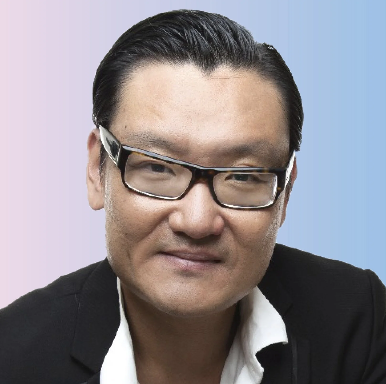Close-up of a man with glasses, short dark hair, wearing a suit and white shirt, smiling, with a blue background.