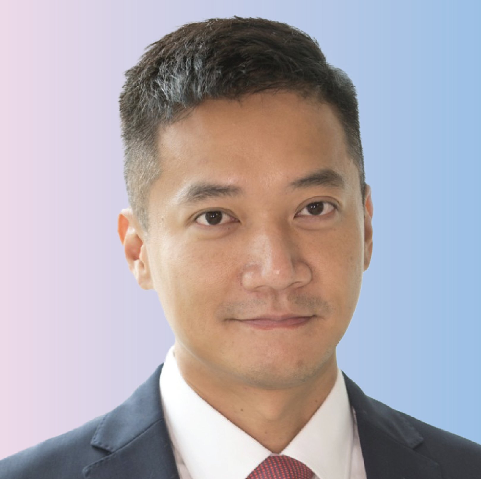 Close-up of a man in a suit with a white shirt and red tie, smiling slightly, against a bluish background.