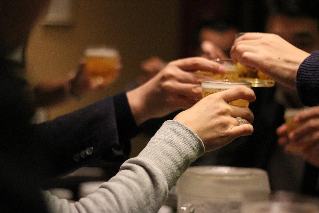 日本の居酒屋で人々がビールを持ち乾杯している様子