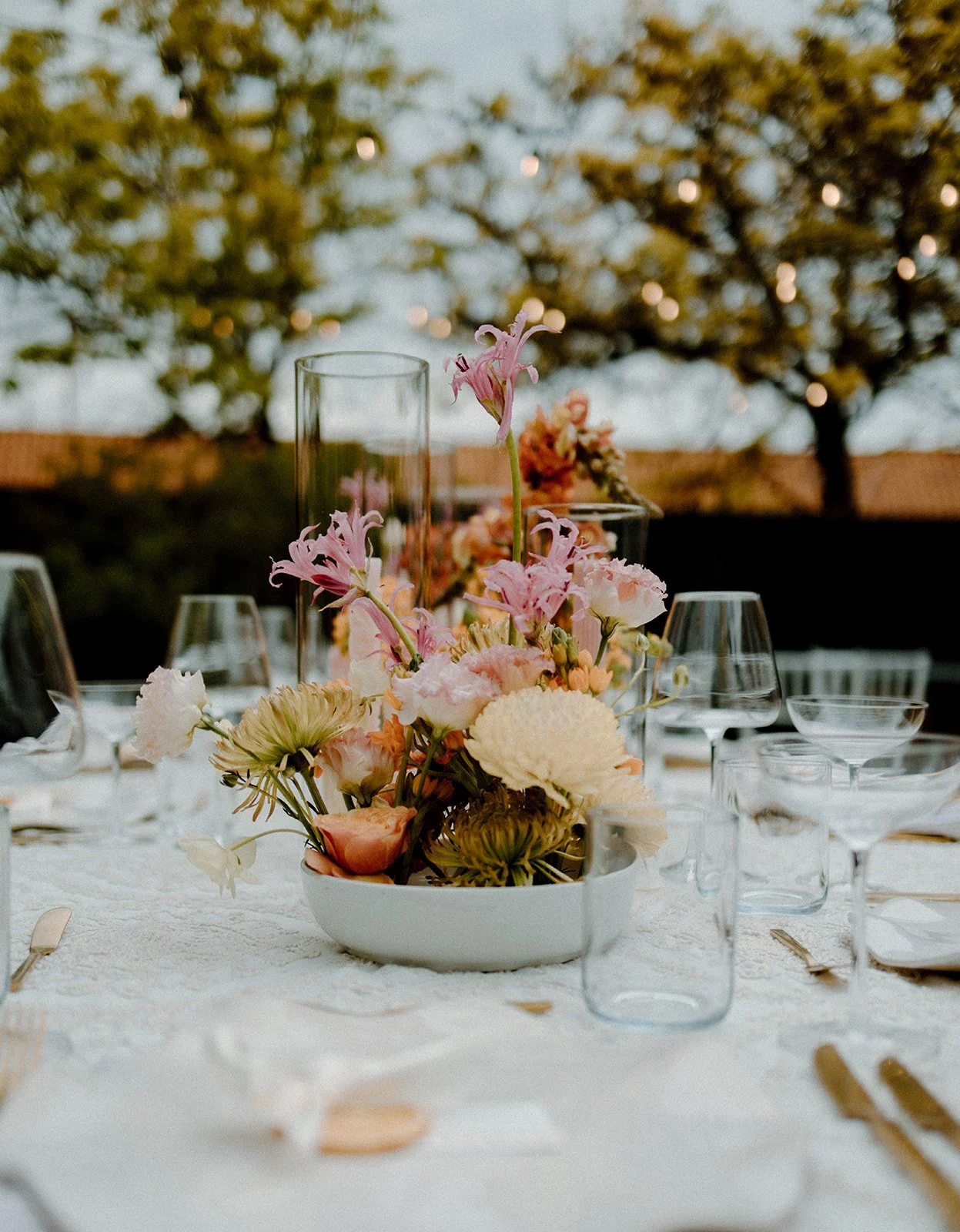 A beautiful flower arrangement on a set table outdoors.