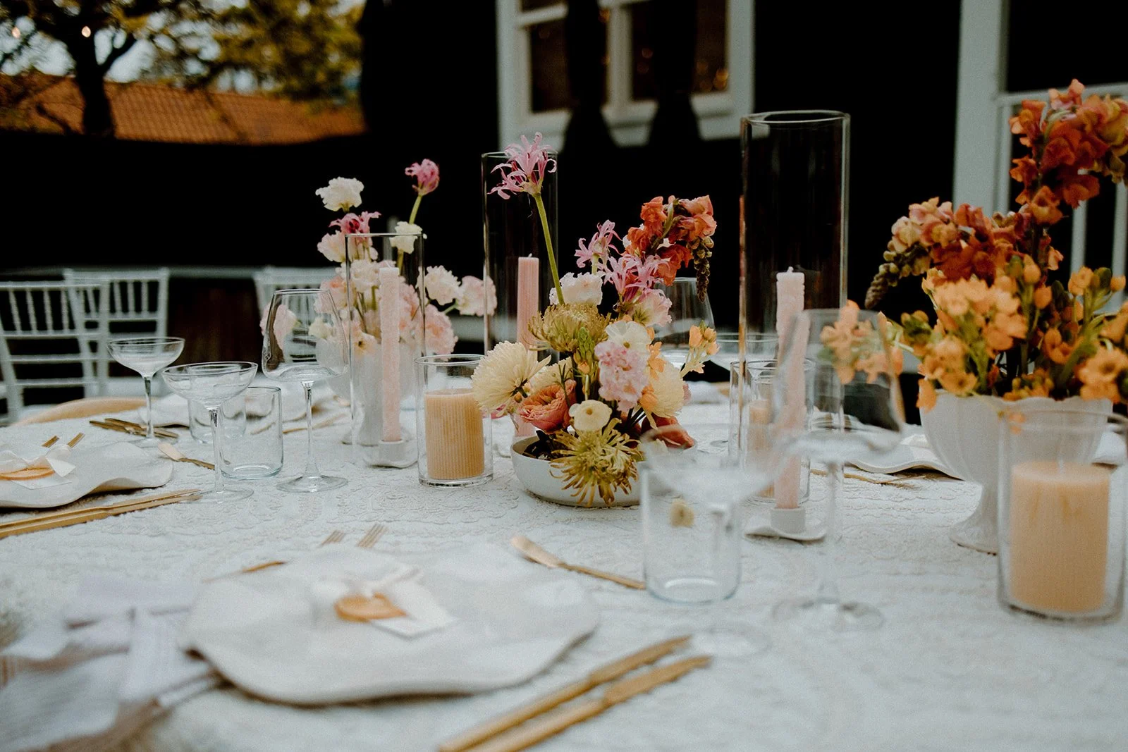 Table set for a special occasion with floral centerpieces, candles, glassware, and napkins.