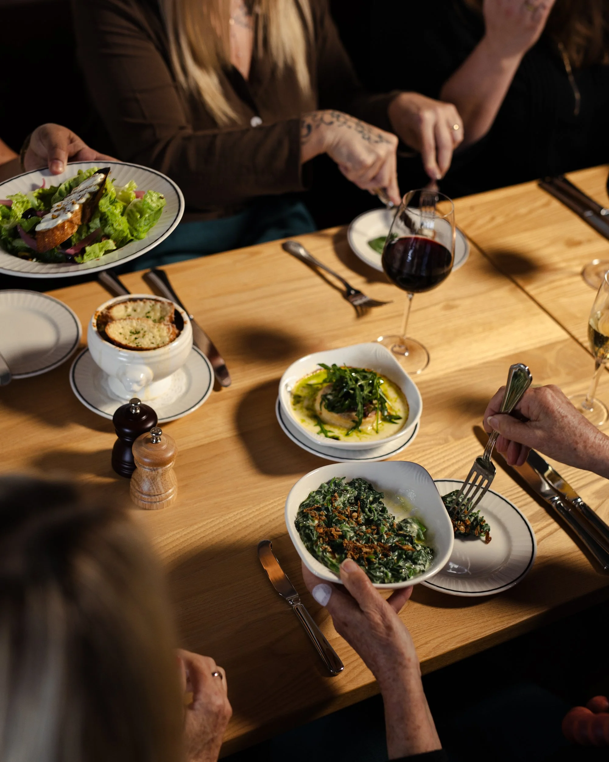 Guests enjoying a table spread of French cuisine and wine at Bistrot Le Mode in Pakenham