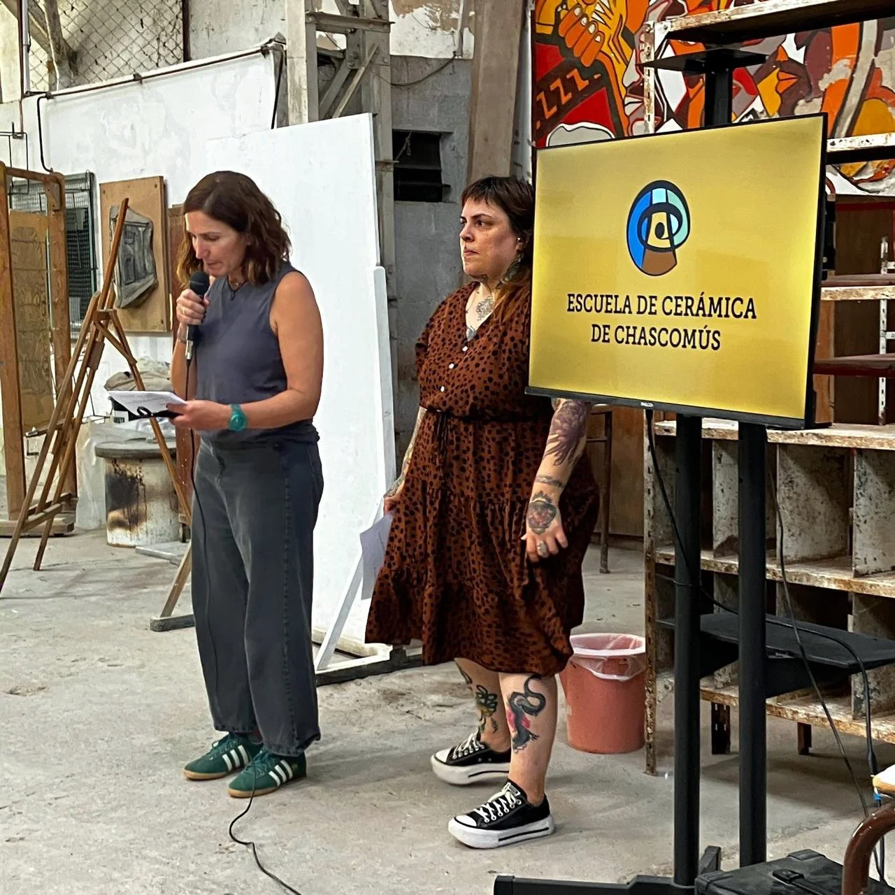 Mujeres en una charla en un taller de cerámica en Chascomús, con un cartel que dice 'Escuela de Cerámica de Chascomús'.