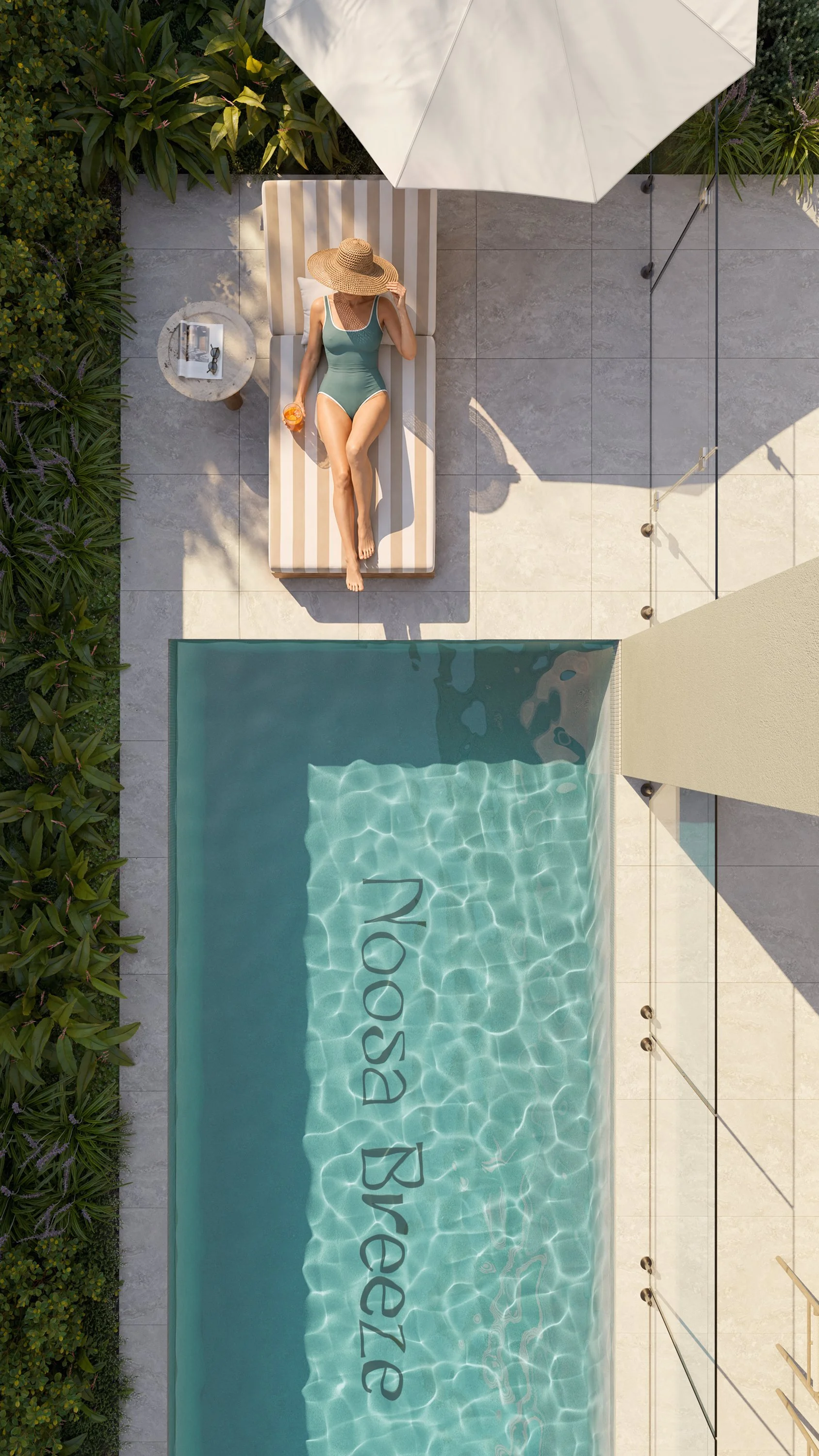 A woman in a swimsuit and large straw hat is lying on a striped lounge chair beside a swimming pool, holding a drink, with a small round table next to her that has sunglasses and a book on it. There is a large white umbrella providing shade, and green foliage surrounds the patio area.