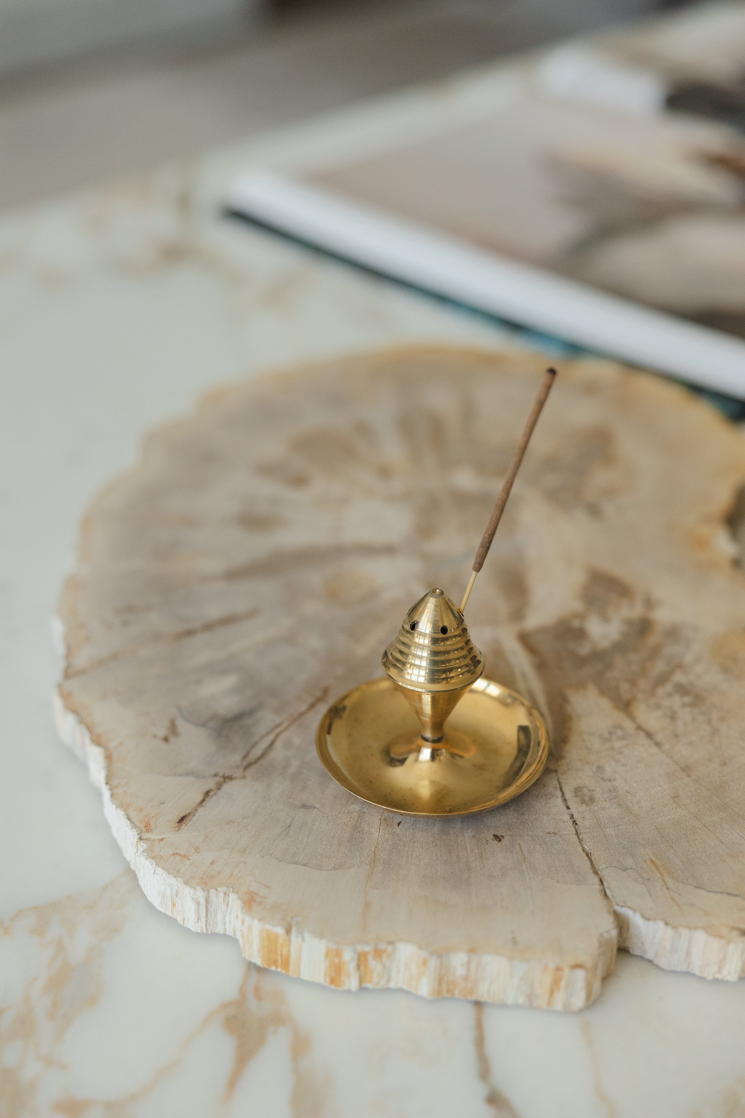 Close-up of a brass pendulum clock on a rustic wooden surface with a wood and white marble background.
