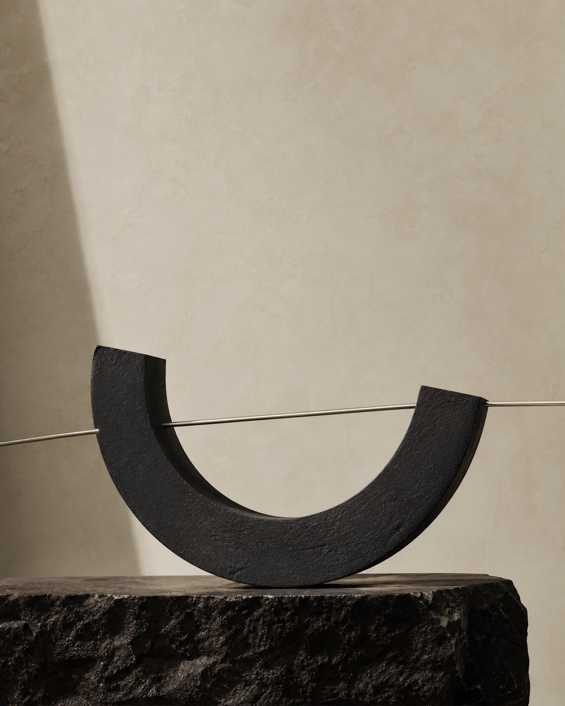 Charcoal open arc crossed by a silver line in warm daylight