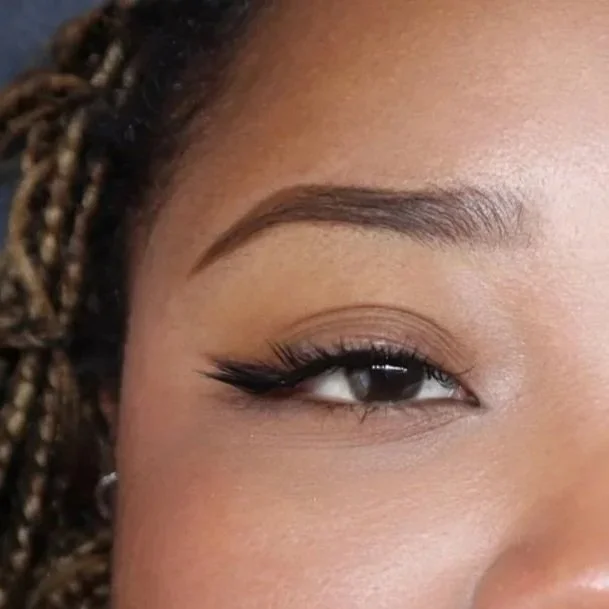 Close-up of a woman's eye with makeup, including eyeliner and shaped eyebrow.
