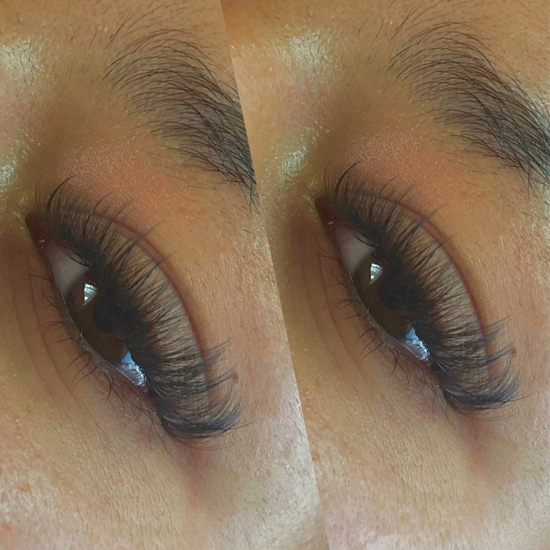 Close-up of a person's closed eyelid with long eyelashes and well-groomed eyebrow hairs.