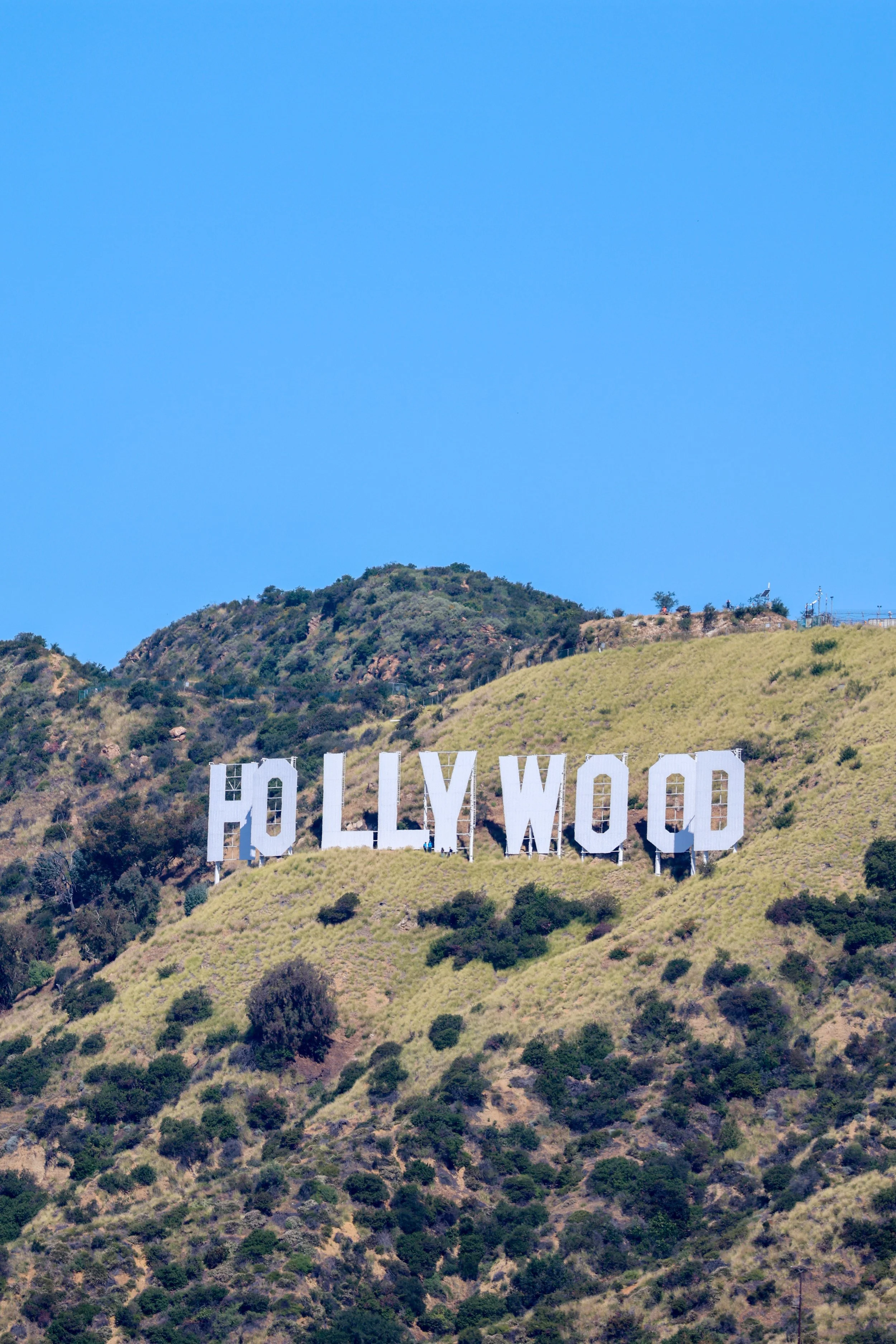 The Hollywood sign on a hillside with a clear blue sky in the background.