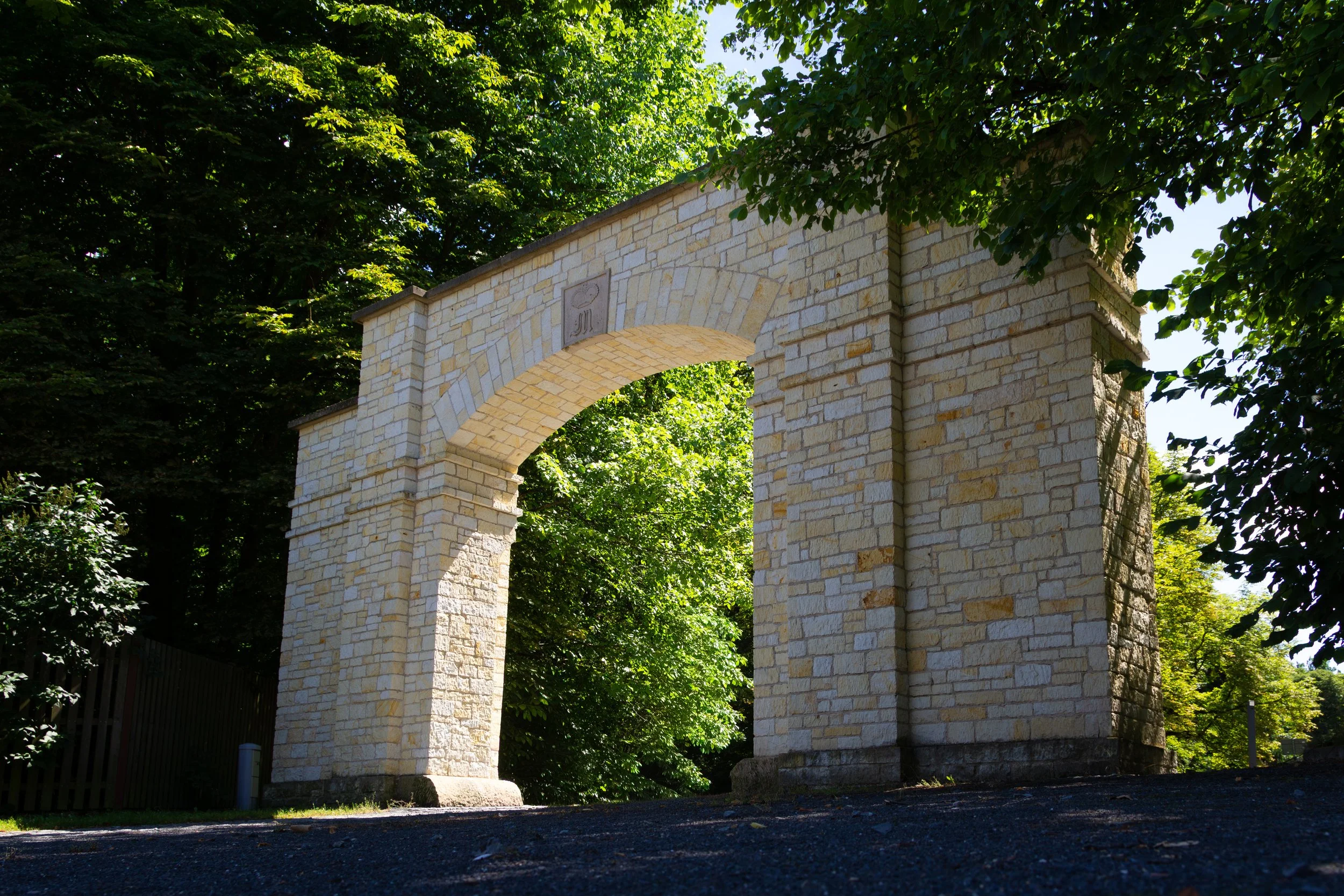 Stone archway monument surrounded by greenery and trees.