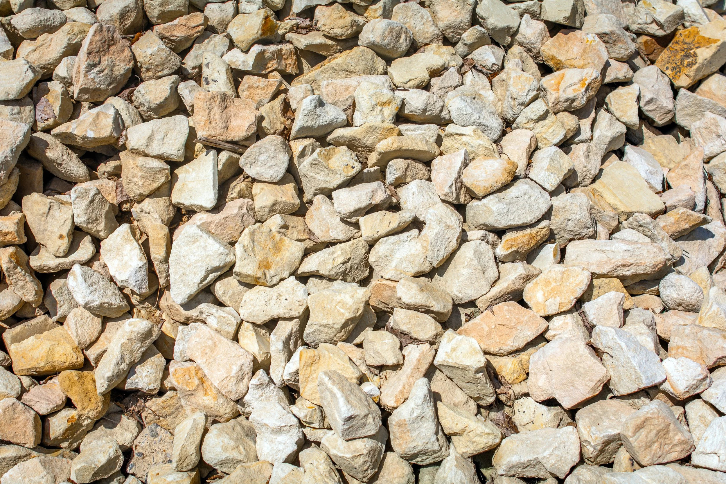 A close-up view of a pile of beige and light brown rocks with rough textures and irregular shapes.