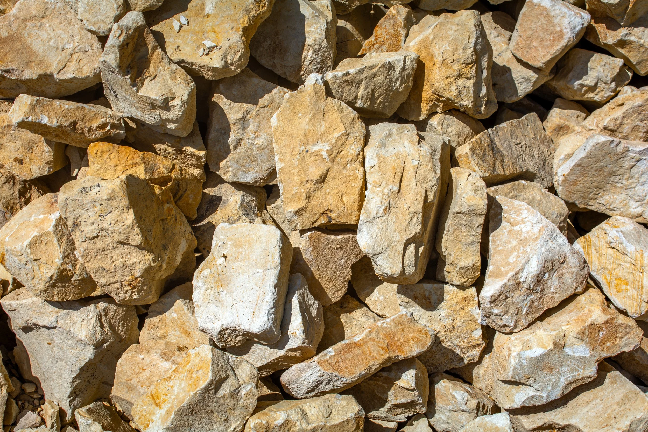 A close-up view of beige and light brown irregularly shaped rocks stacked together.