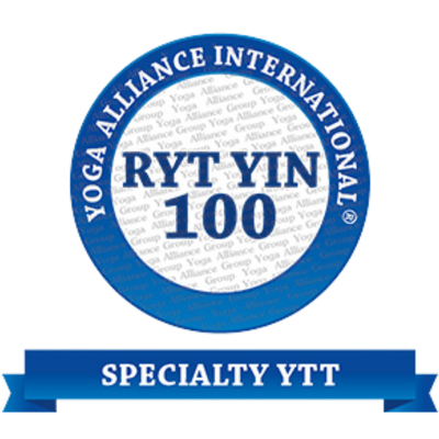 Circular emblem for Yoga Alliance International celebrating 100th anniversary, with a blue border, white background, and blue text, and a blue ribbon at the bottom reading 'Specialty YTT'.