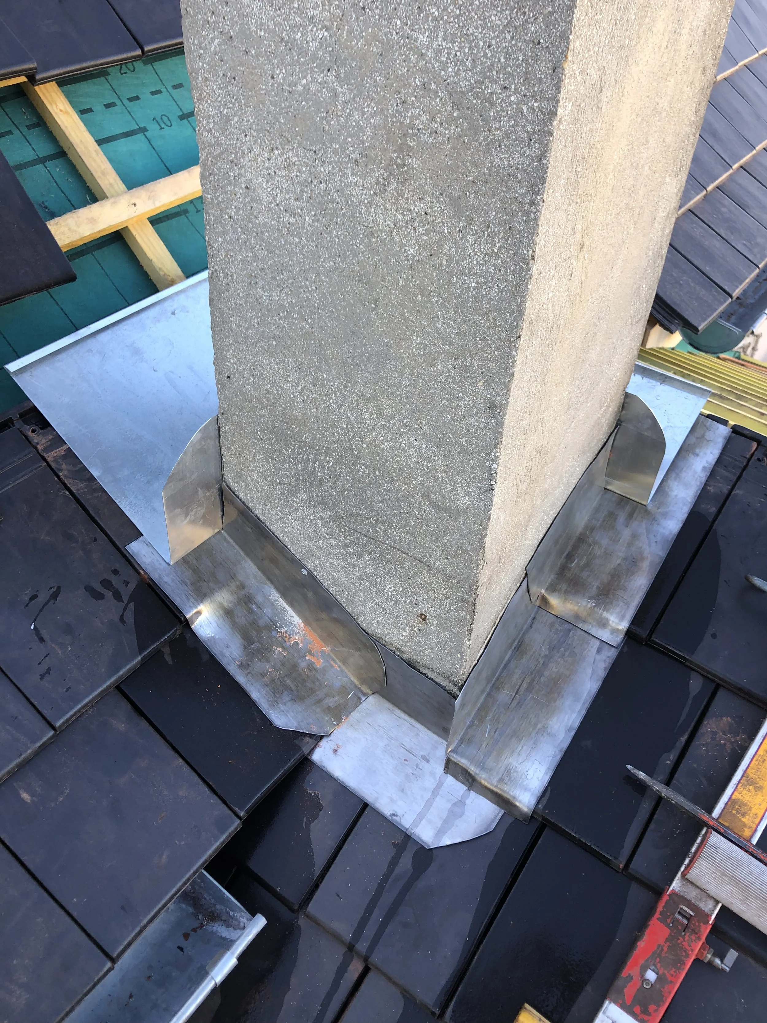 Une cheminée en construction, entourée de matériaux de couverture et de support en métal.