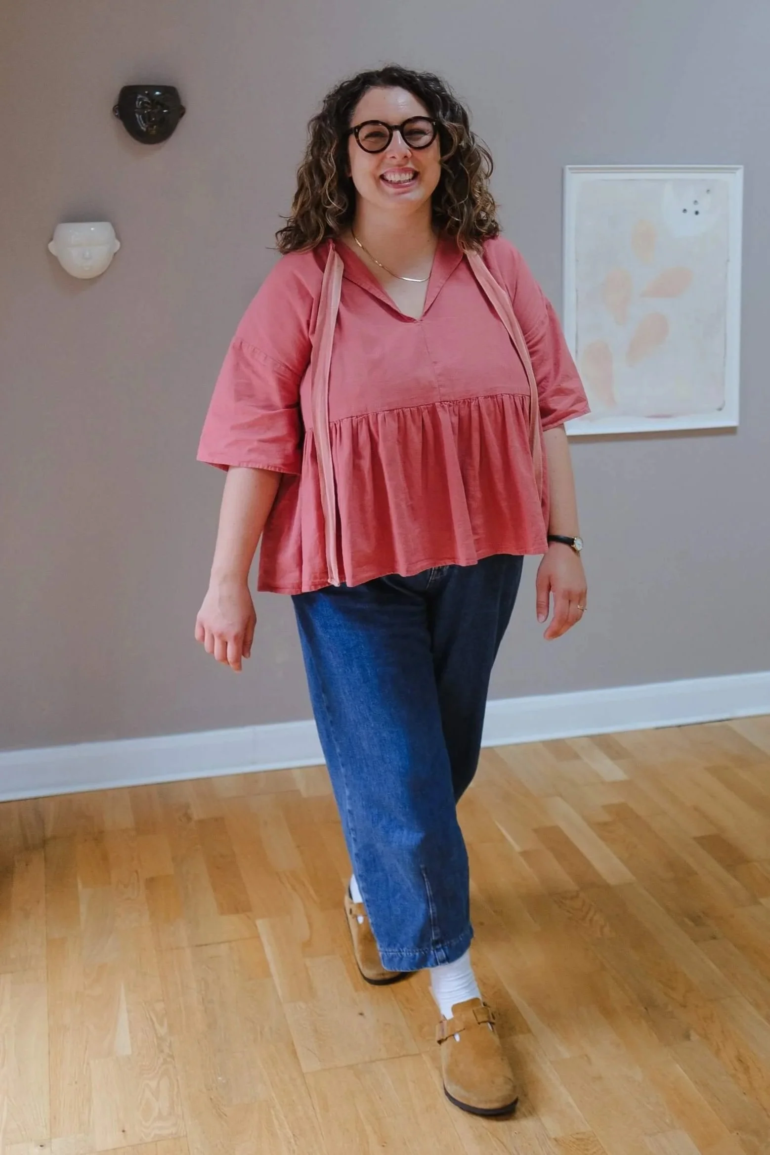 Portrait of Tash Hallett, a doula based in Sheffield, wearing a pink top and glasses against a light neutral background.