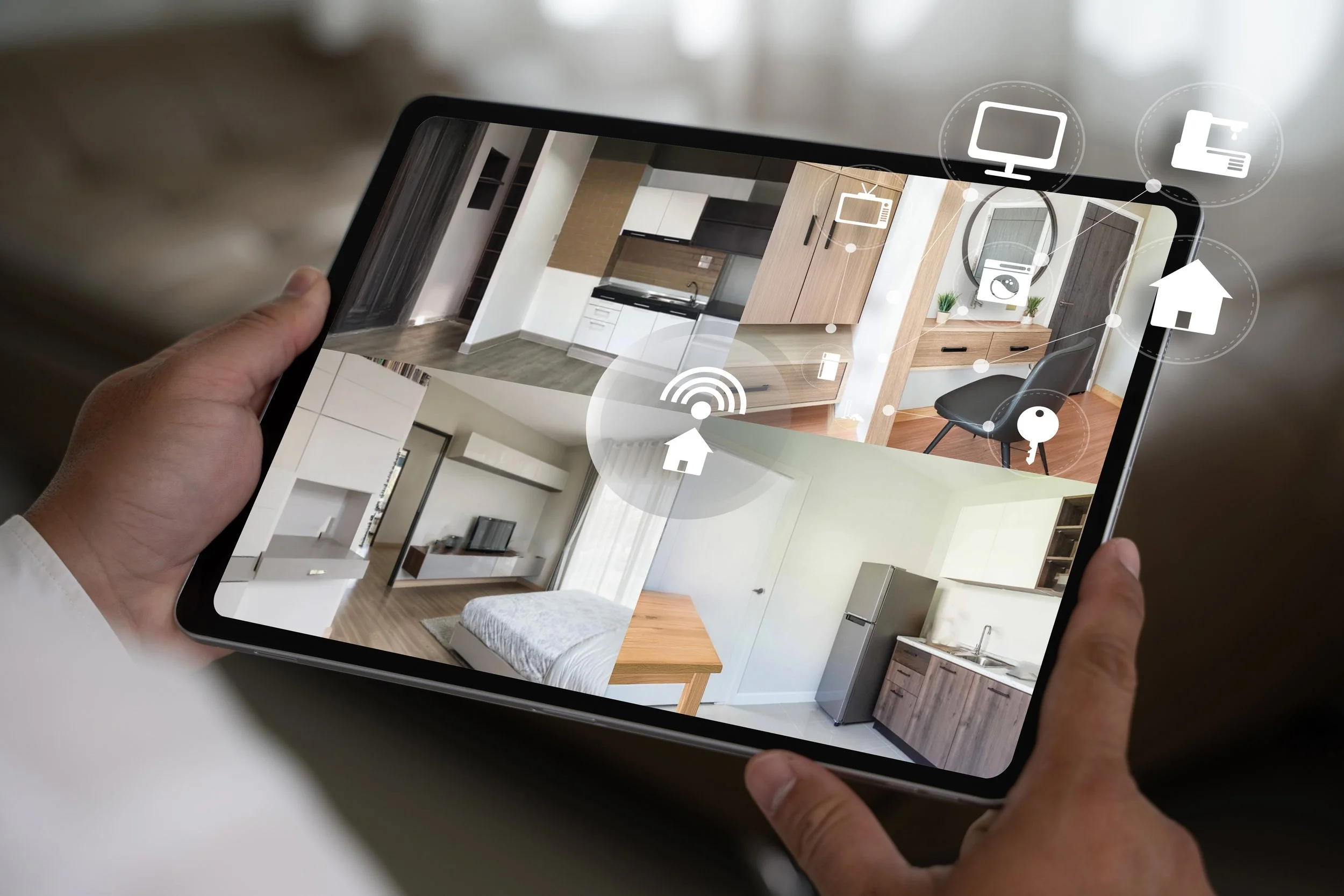 A person holding a tablet displaying images of a modern kitchen, living room, and bedroom interiors.