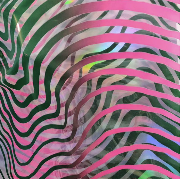 Close-up of a colorful zebra stripe pattern in pink, green, black, and blue hues.