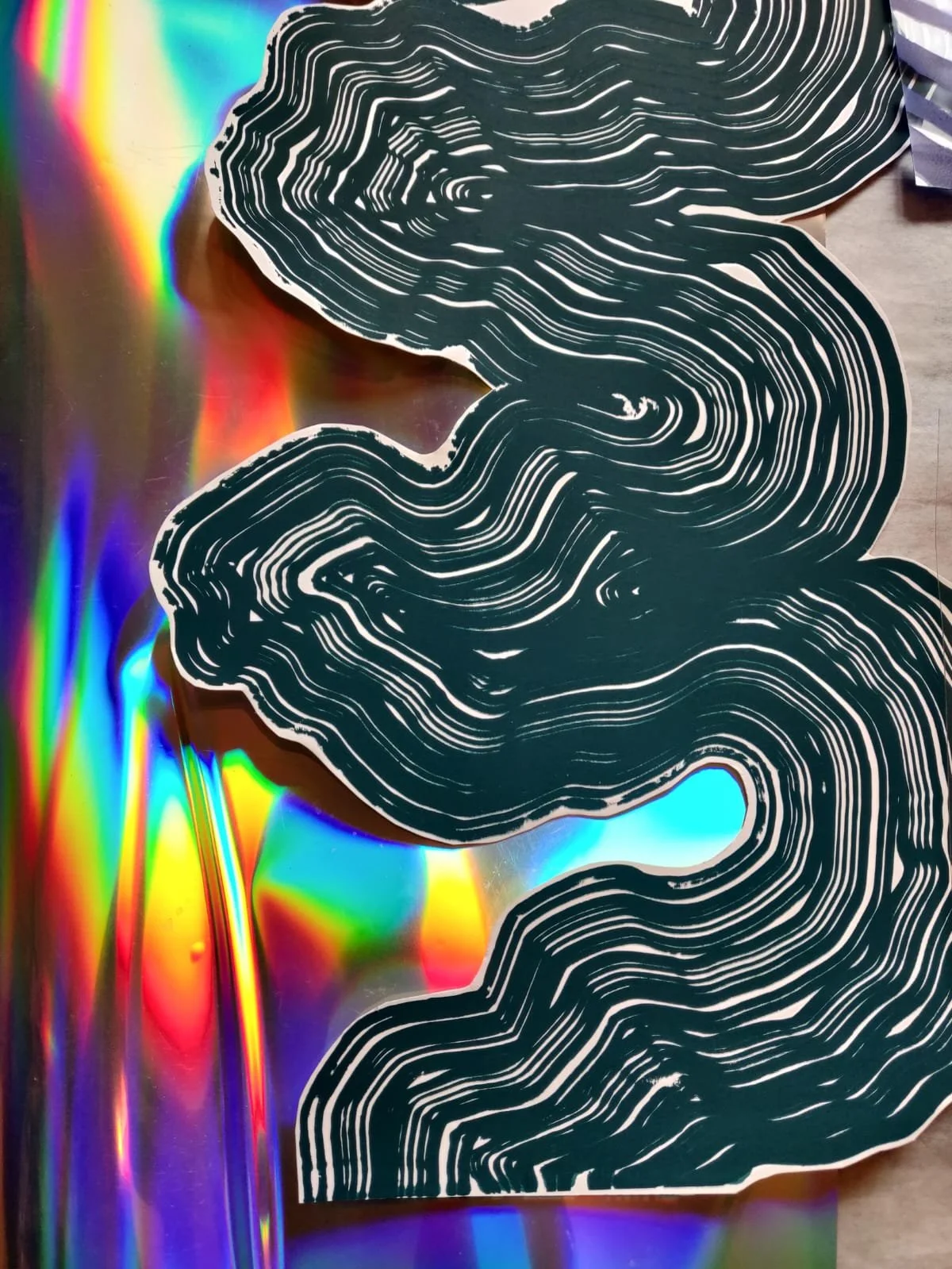 Black and white layered paper cutout resembling a face on holographic surface.