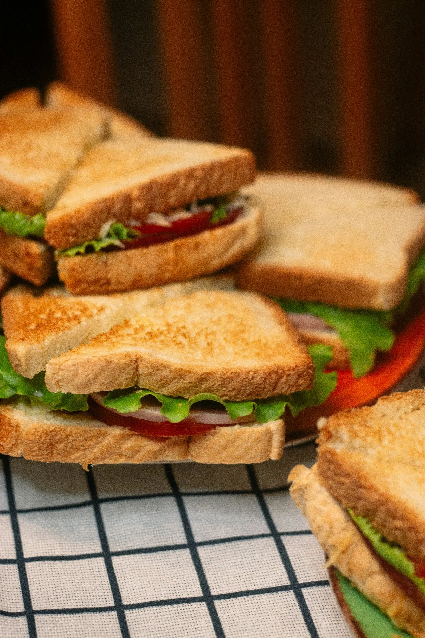 İki adet tostlu sandviç, içlerinde marul, domates ve jambon var, bir tanesi açıkta kalmış.