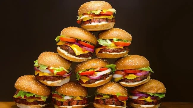 Dallas usulü cheeseburgerler, domates, marul, soğan ve turşu ile hazırlanmış, en üstte birkaç tane cheeseburger ile piramit şeklinde düzenlenmiş.