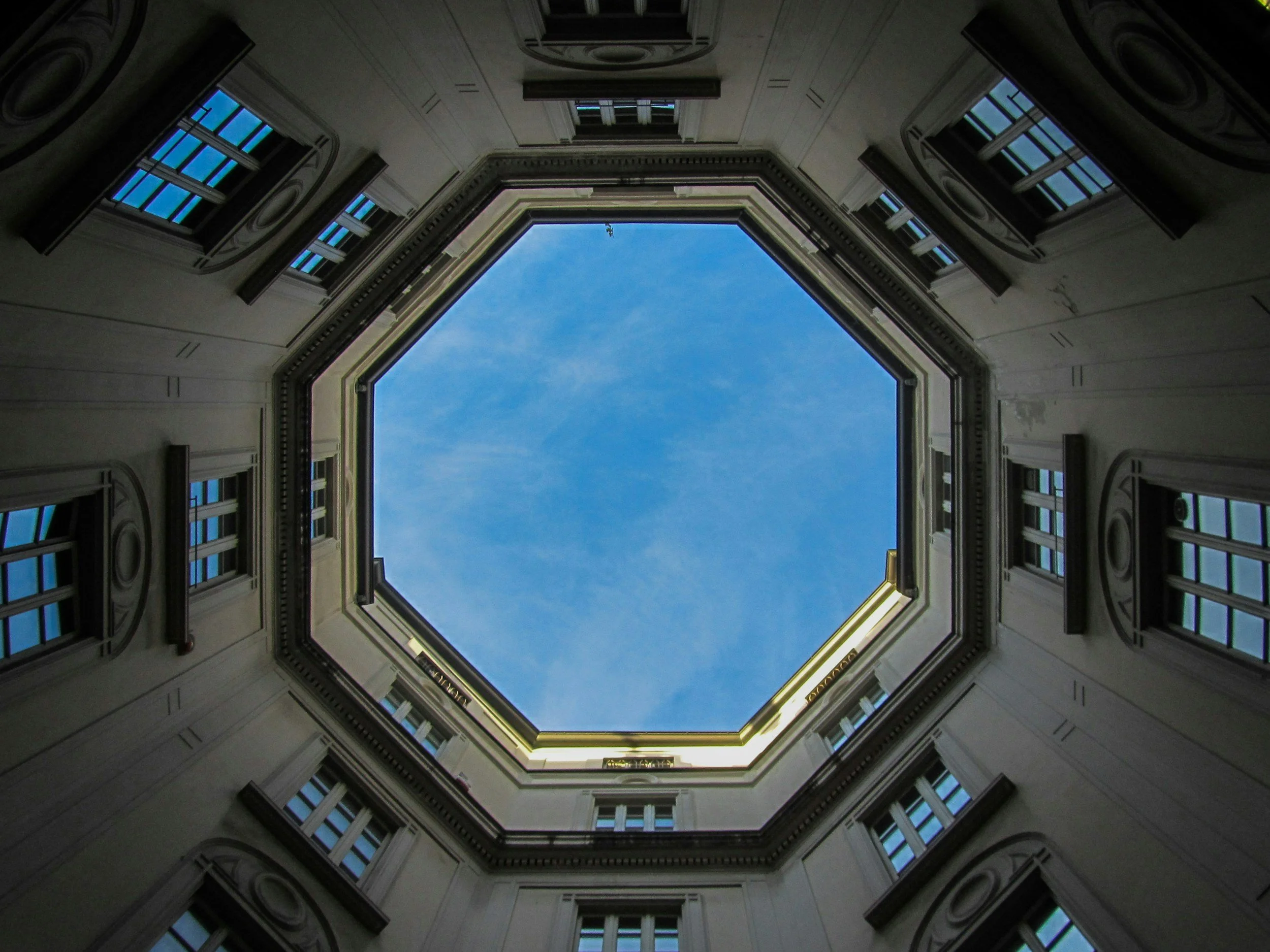 View looking upwards through an octagonal courtyard towards the blue sky.