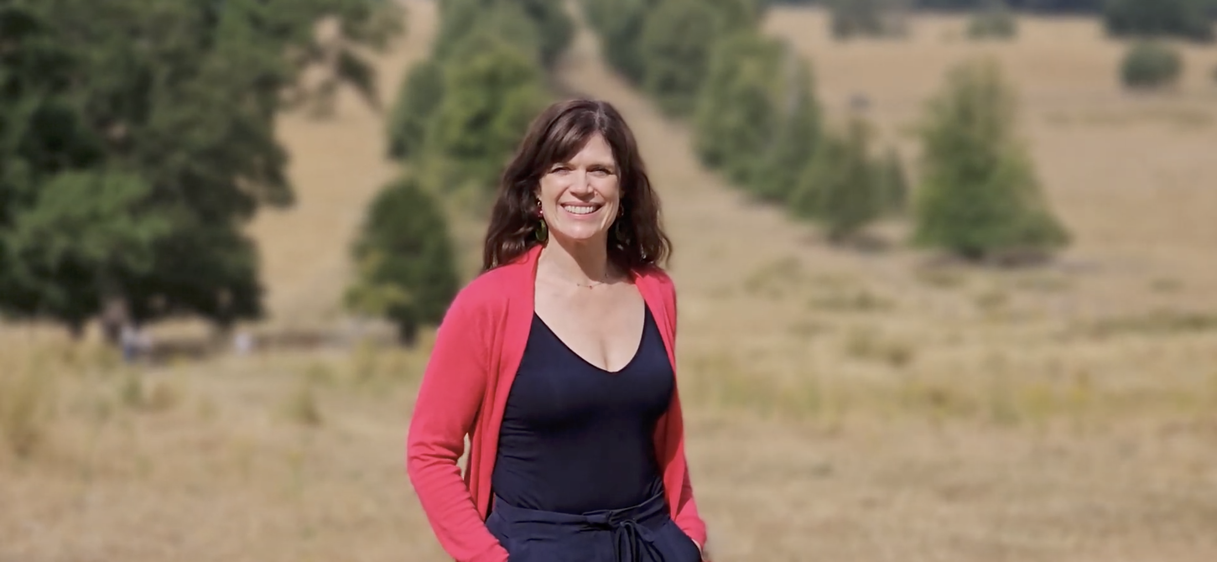 Katie, founder of Optimise, outdoors in a natural landscape.