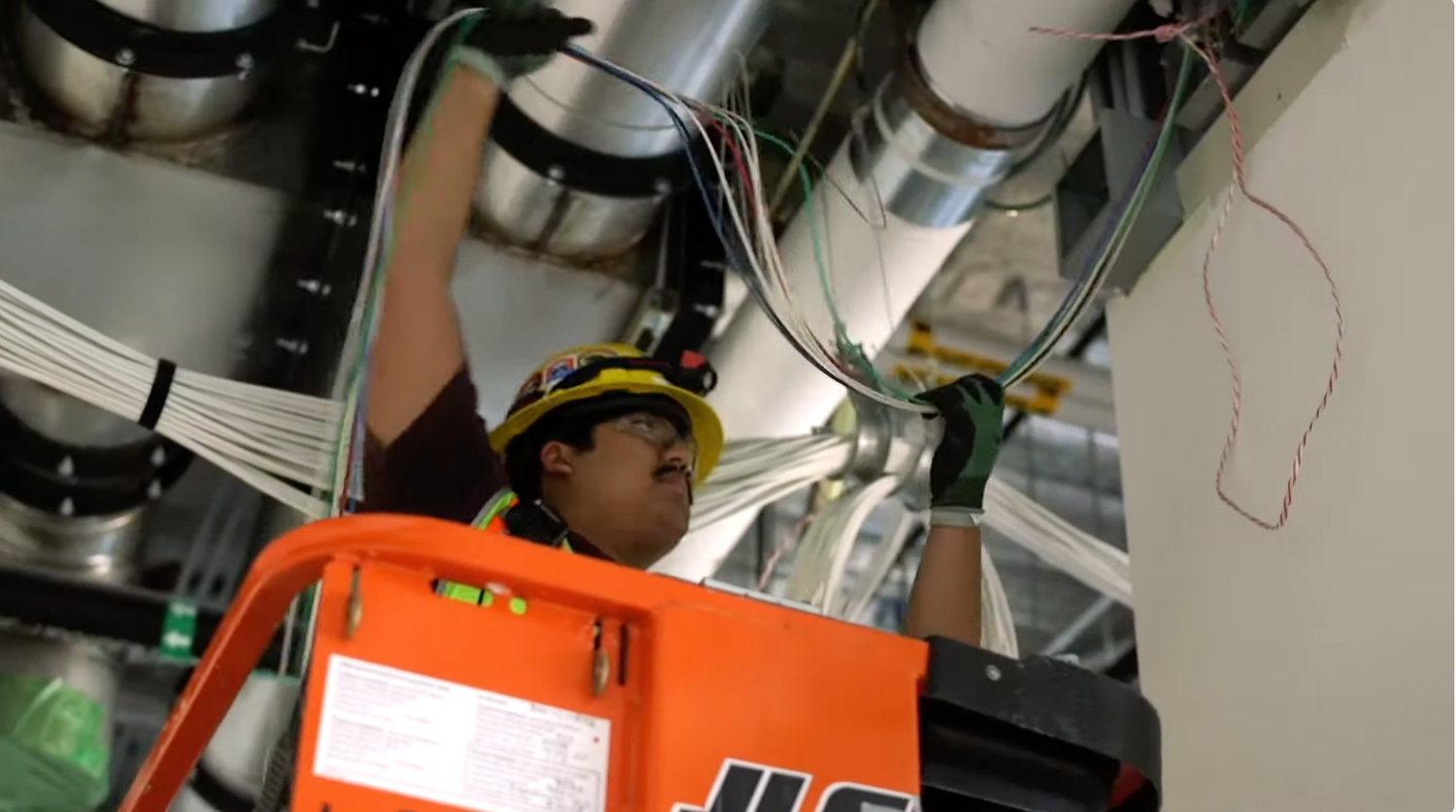 An electrician on a lift feeding wire