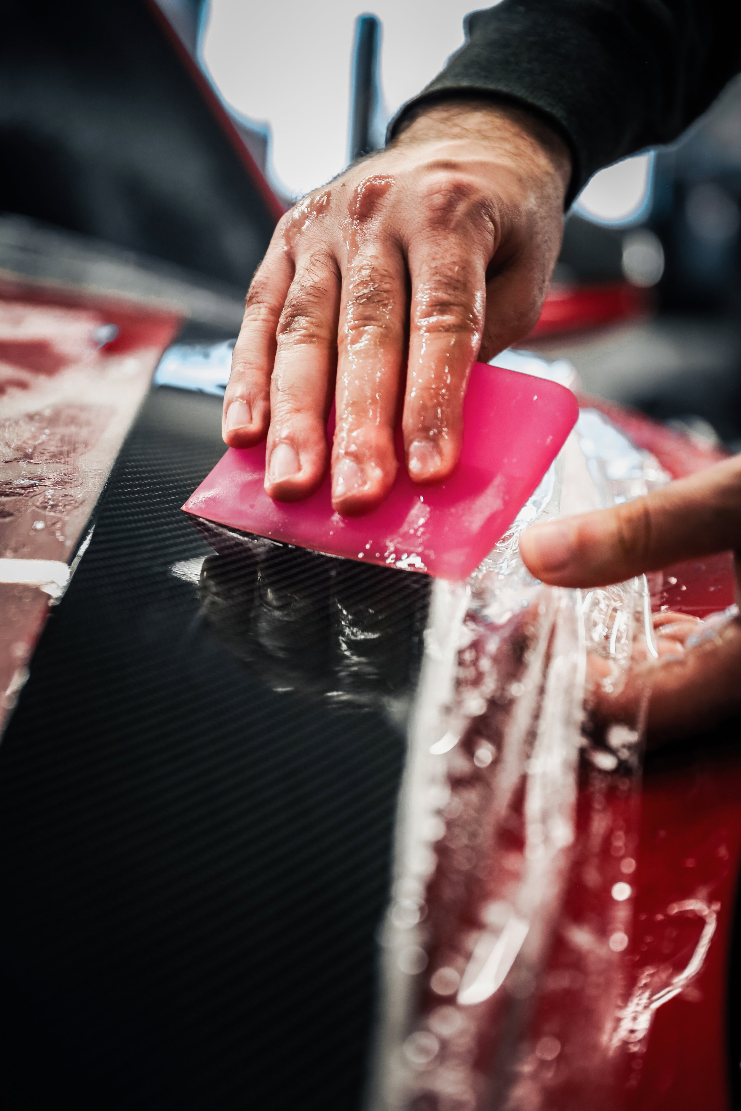 Wrapster workers squeege the liquid out of Paint Protection Film on the Red Porsche GT3 RS in Örebro, Sweden, photographed by Annika TheVolvoGirl Miftakhova.