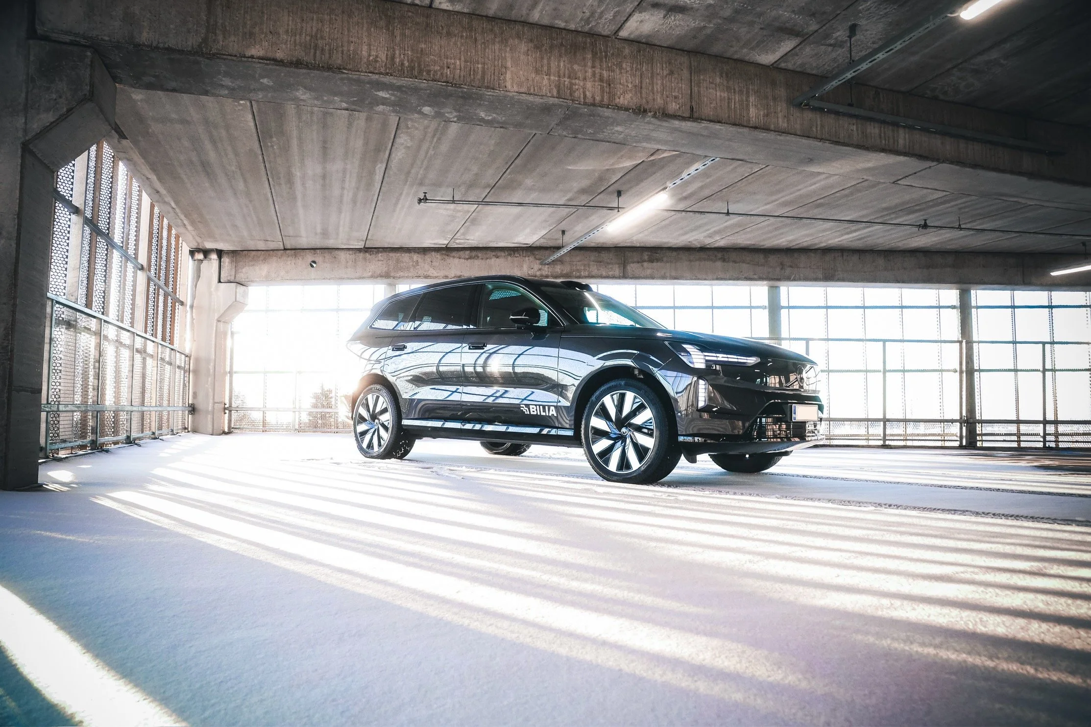 Black Volvo EX90 photographed in winter snow of an open parking lot and baclit by sun in Helsinki by Annika TheVolvoGirl Miftakhova 