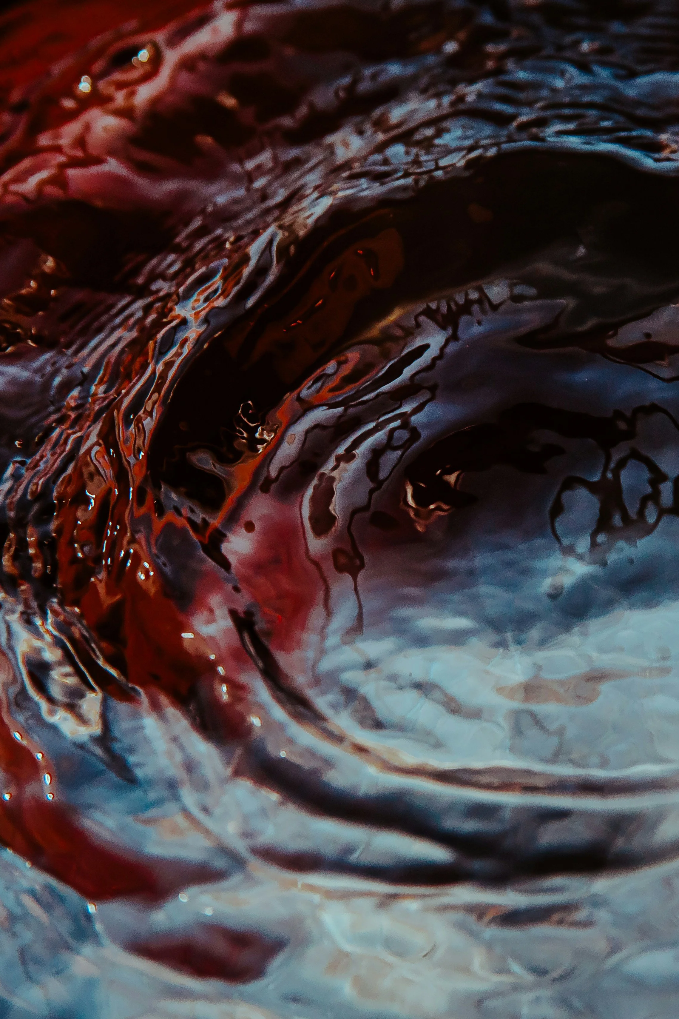 Close-up of swirling red and black liquid with hints of white.