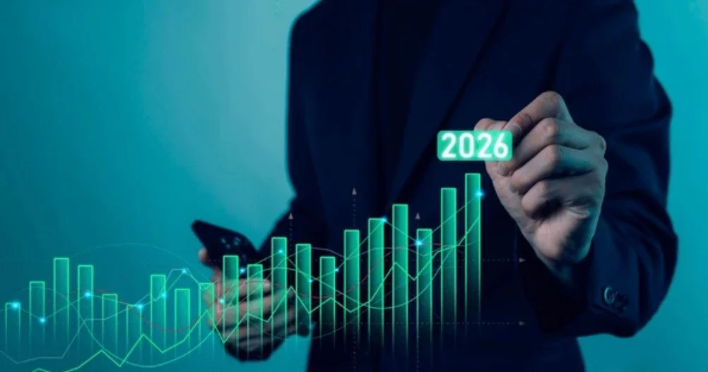 Persona en traje negro tocando una gráfica de barras digitales y mostrando el número 2026, con fondos de luces verdes y azuladas.