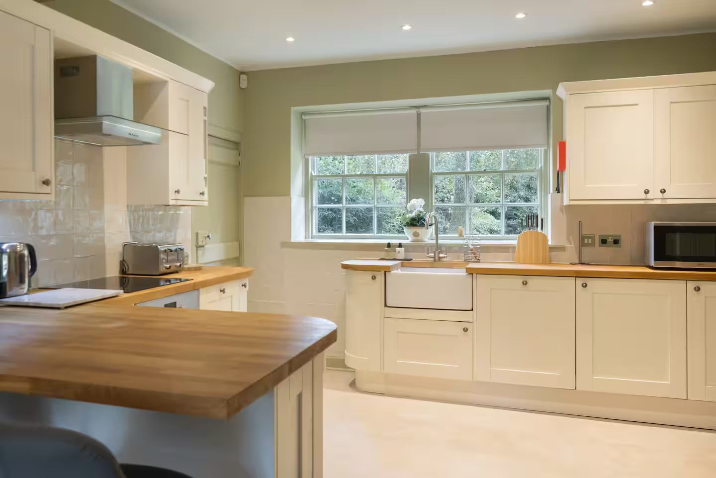Bright kitchen with white cabinets, wooden countertops, a large window, and modern appliances.