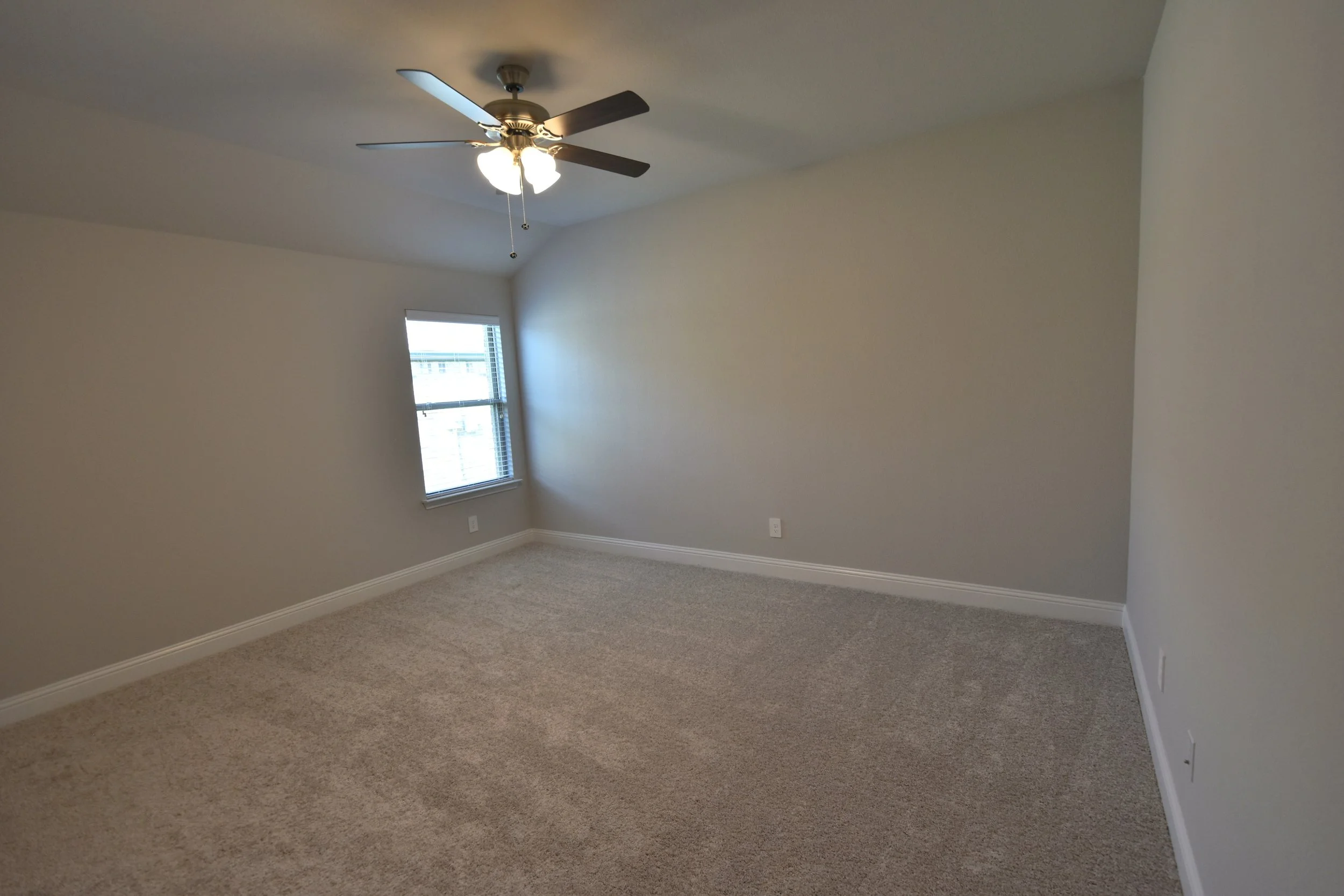 Empty room with beige carpet, light-colored walls, a ceiling fan with lights, and a window with blinds.