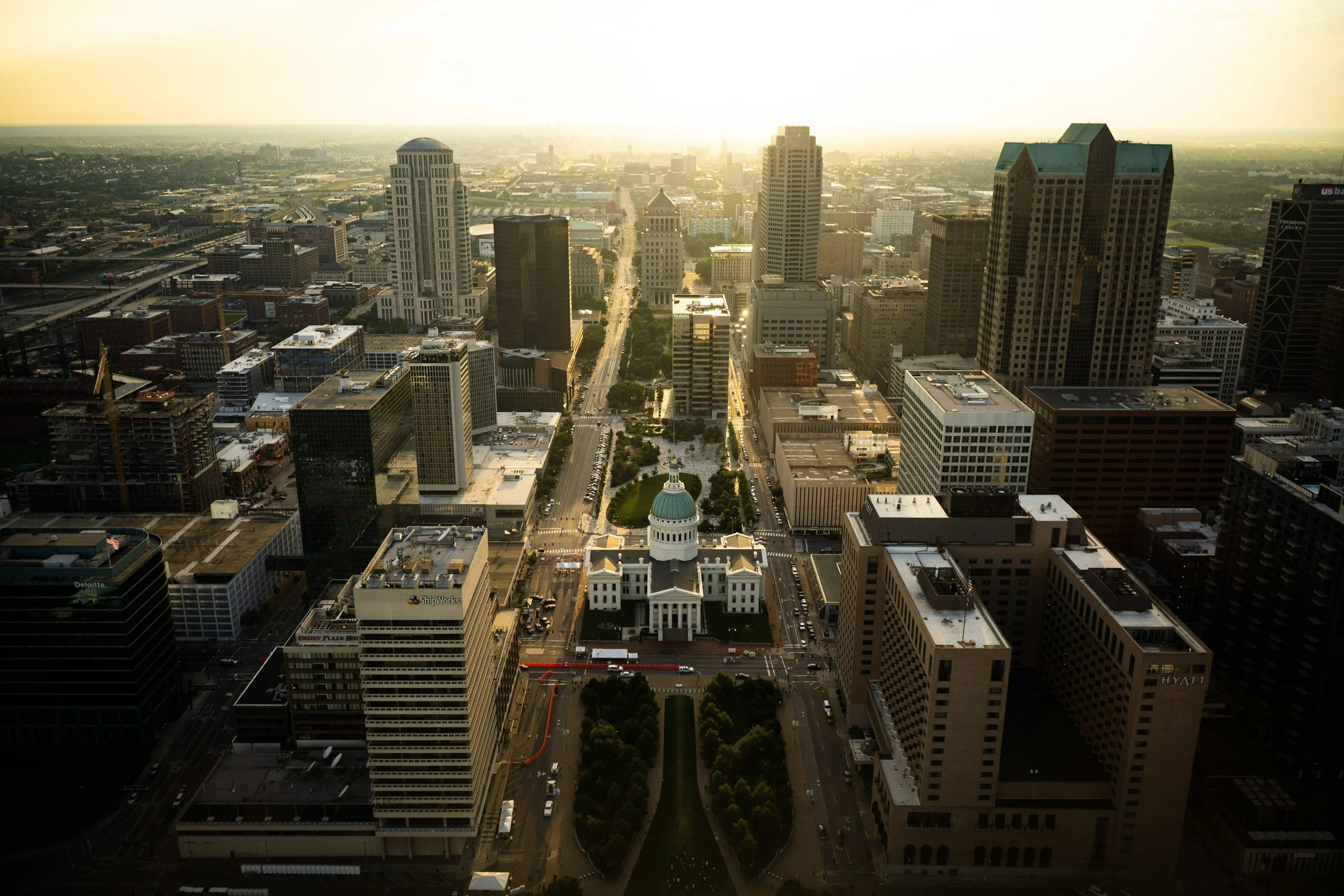 Aerial view of downtown city with tall skyscrapers, a domed building, and streets during golden hour.
