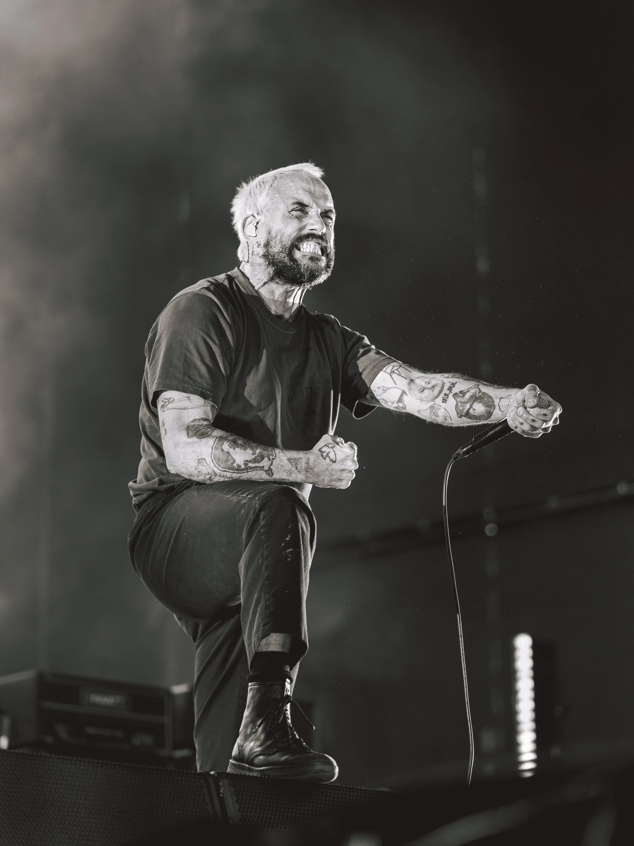 energetic black and white picture Joe Talbot singer of IDLES band punching air with his fists while performing live at Budapest Park, Hungary, by Levente Barabás aka fractionsofmyPOV