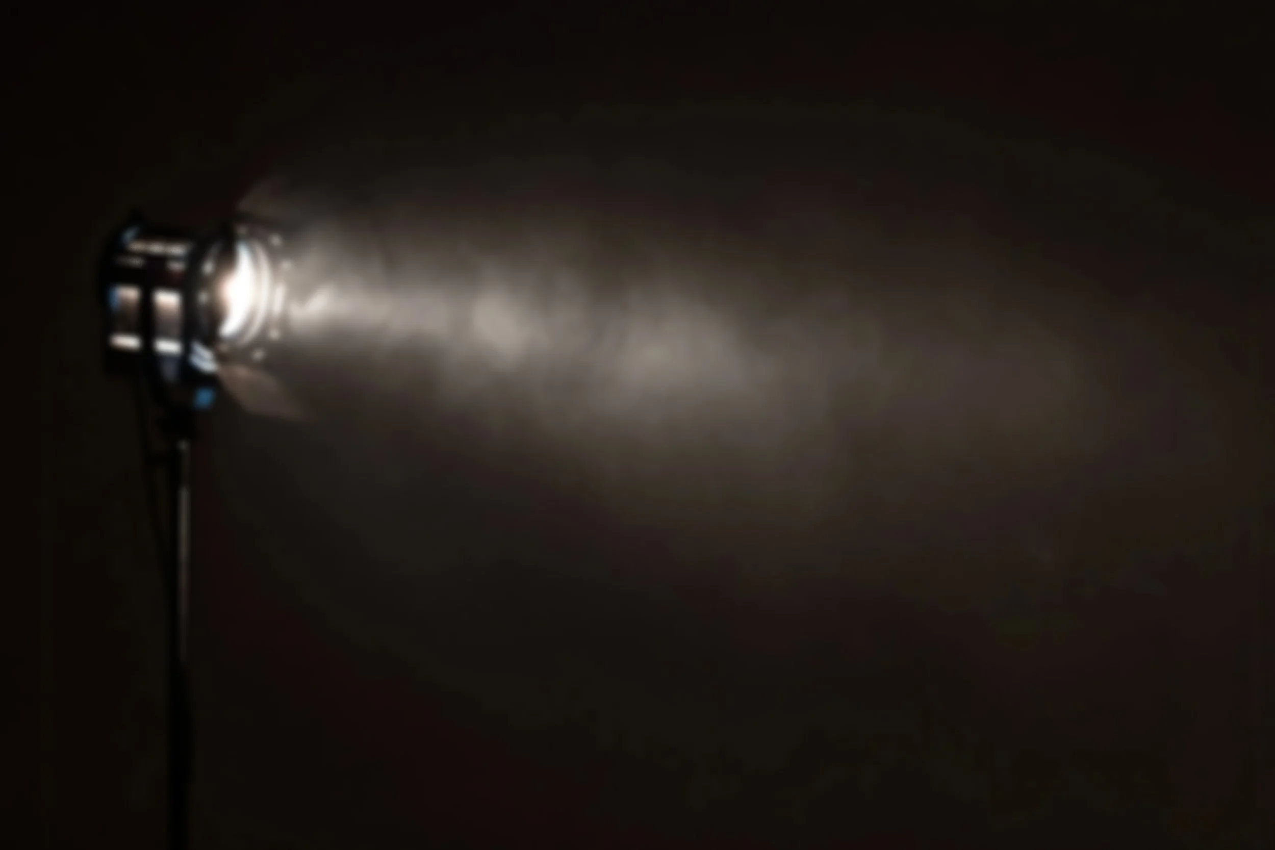 A flashlight shining a bright beam of light into a dark space.