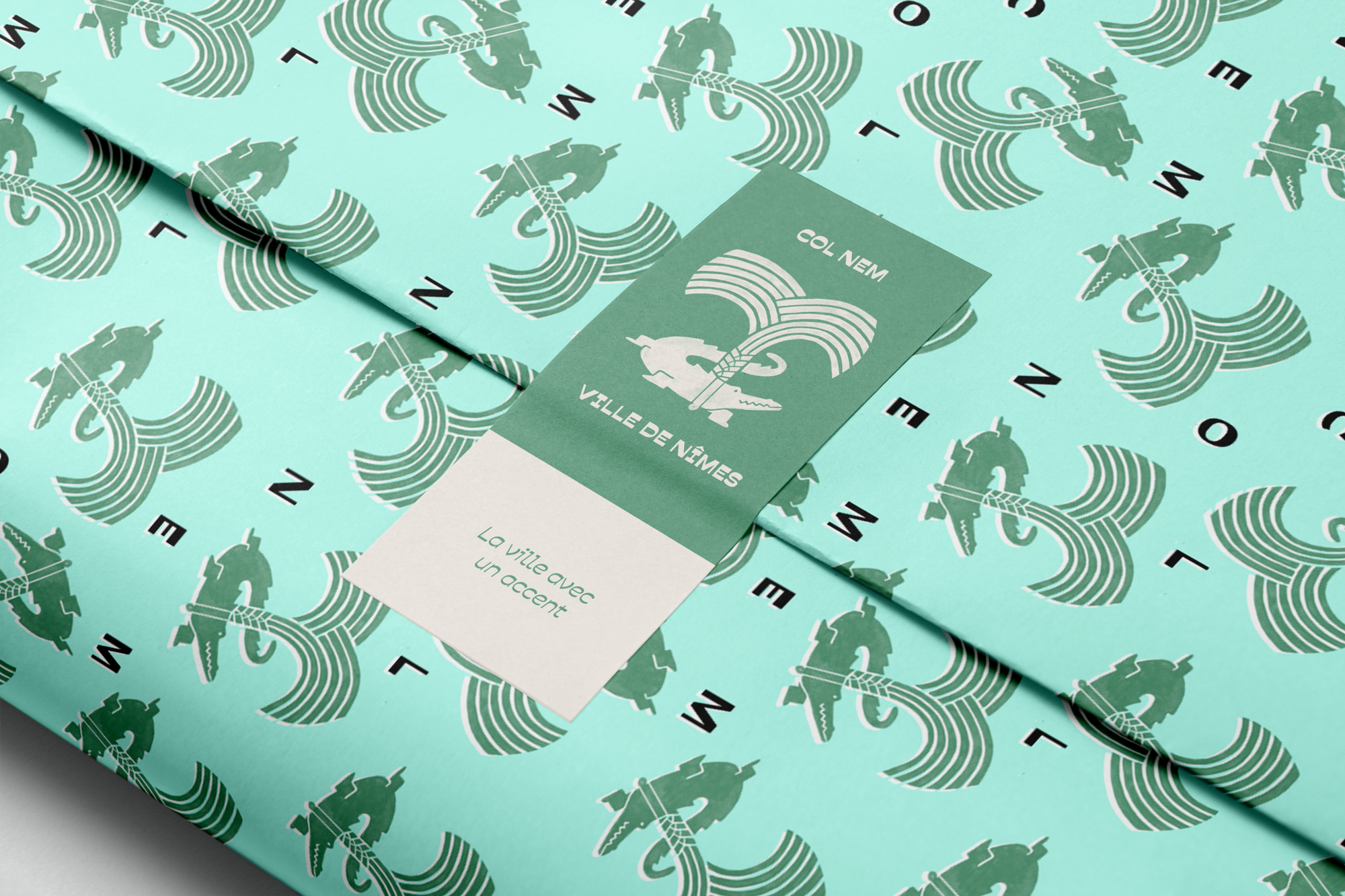 Close-up of themed wrapping paper featuring stylized images of a knight, rainbow, and text 'COL NEM' in black, green, and white colors with a label reading 'COL NEM' along with additional French text.