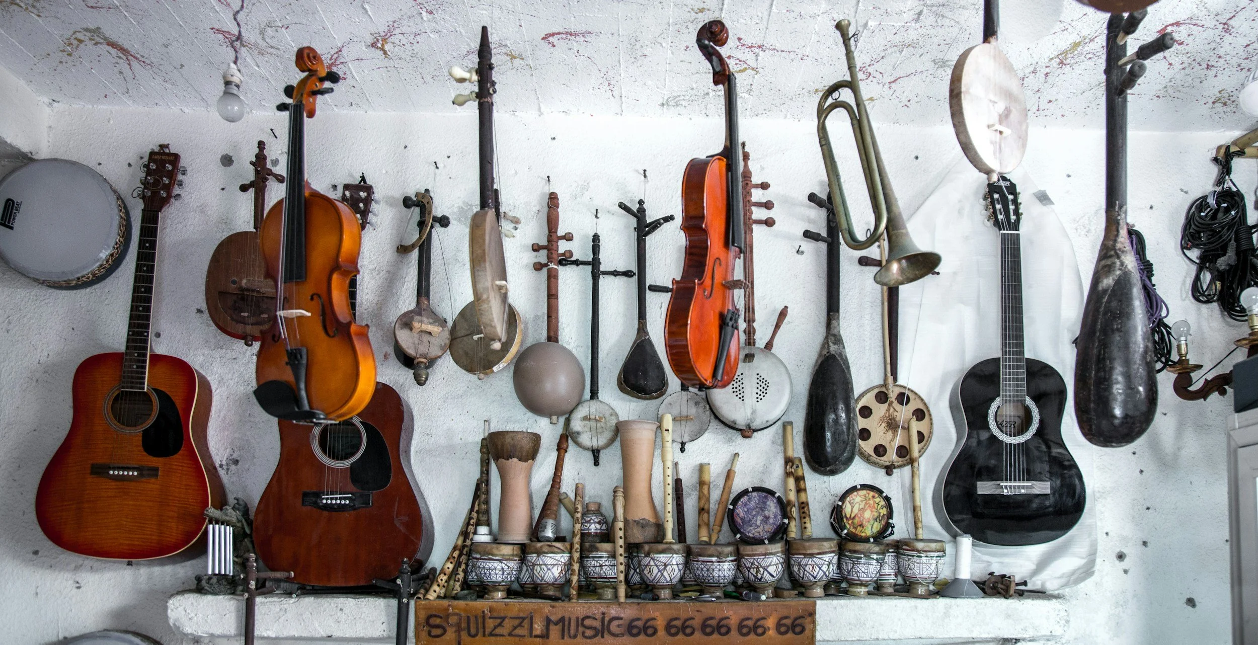 A wall display of musical instruments including guitars, violins, a trumpet, drums, and various percussion instruments.