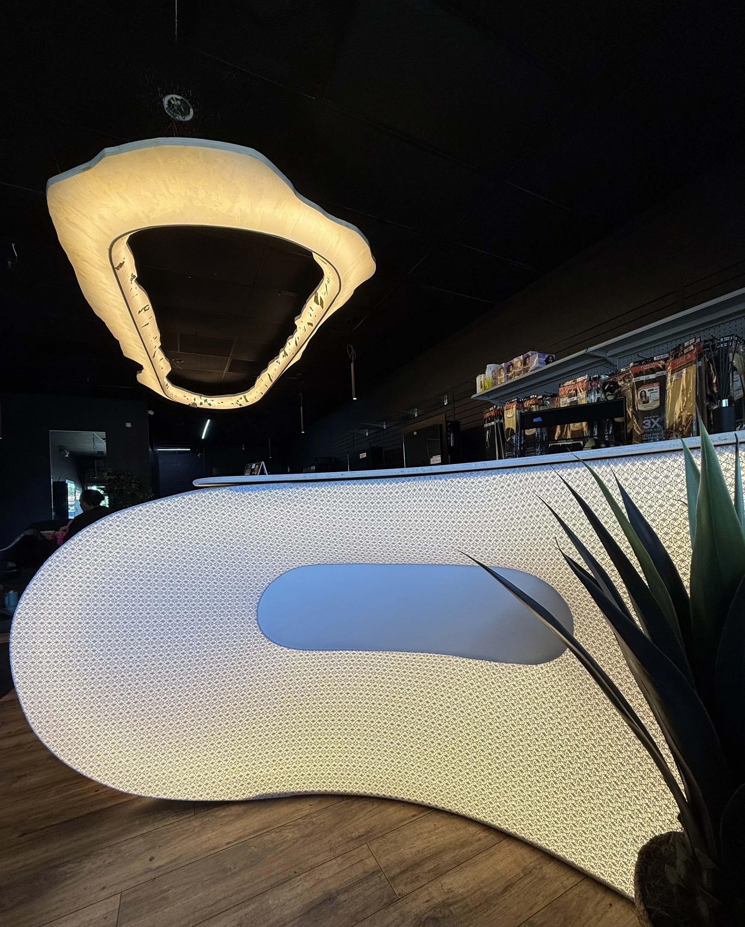 Interior view of a modern space with a glowing, curved, luxury and futuristic front desk and ceiling light