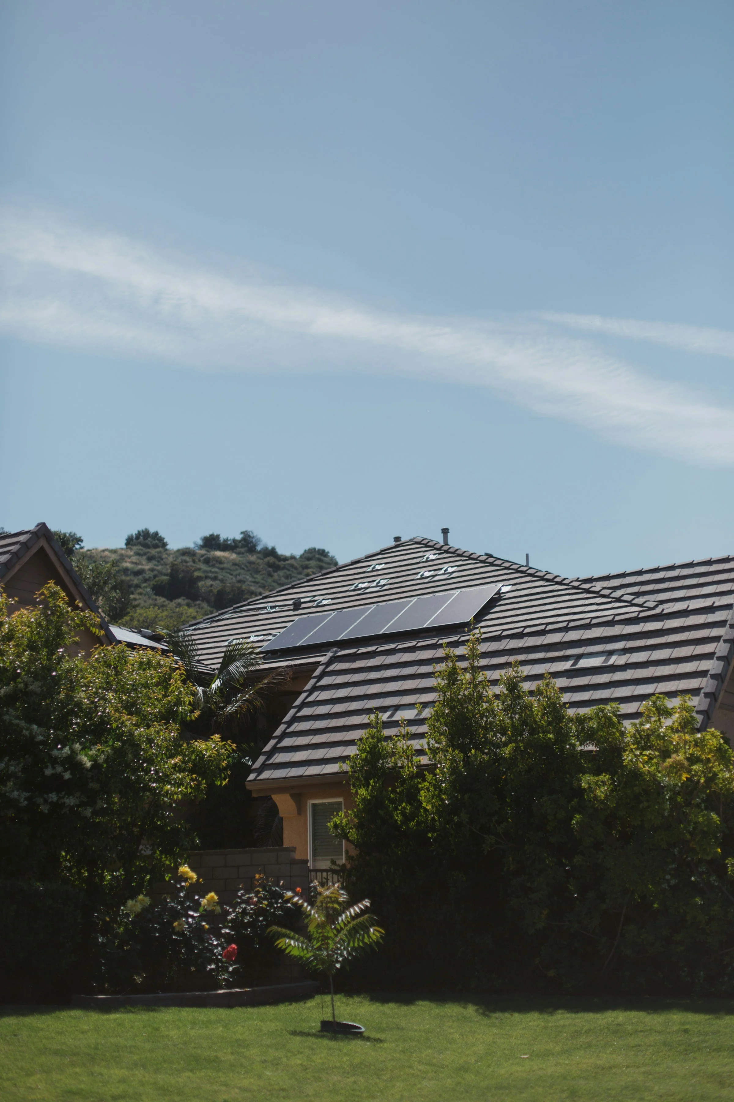 Residential home with rooftop solar panels in a green garden setting.