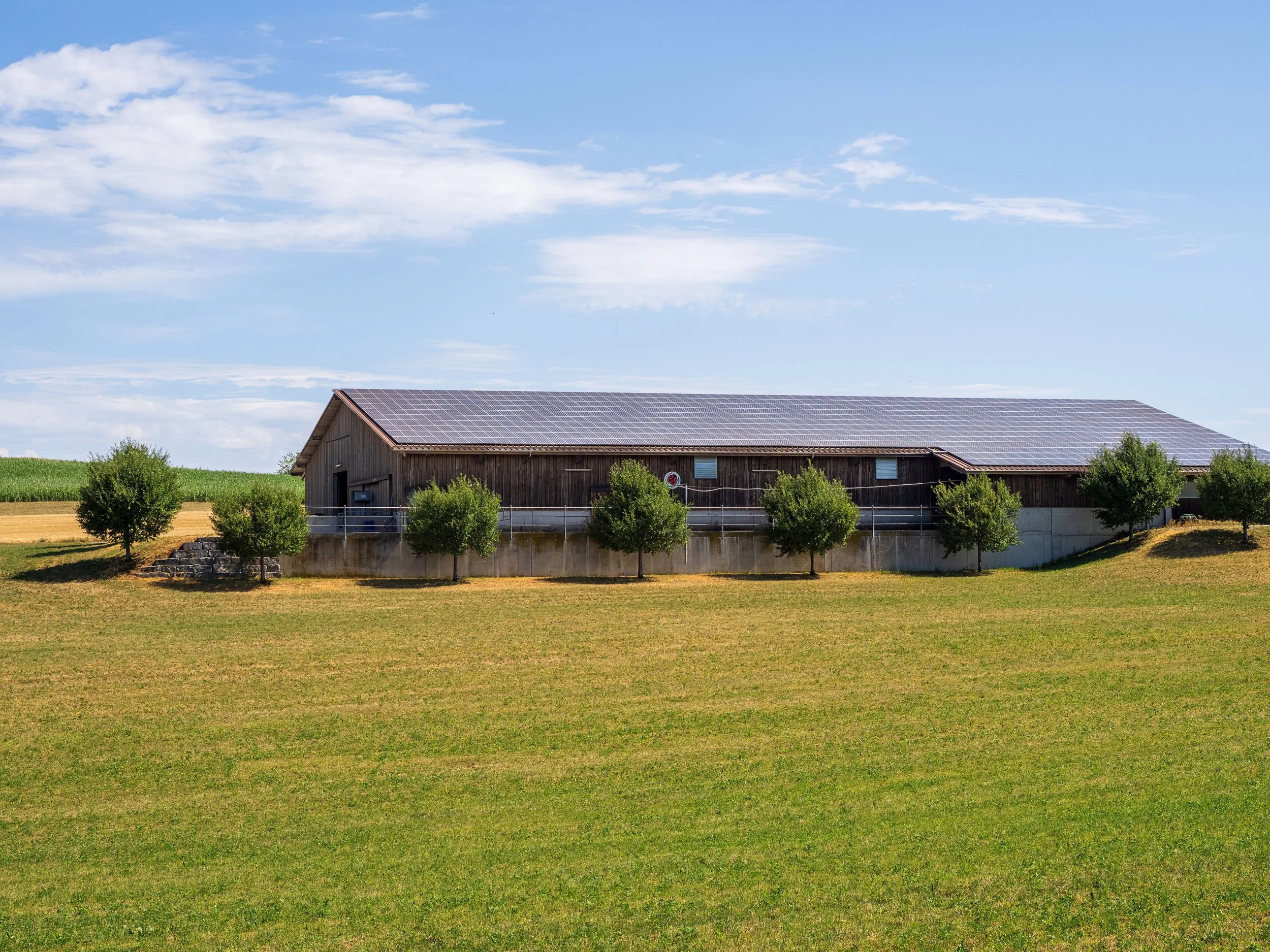 Agricultural building with rooftop solar panels surrounded by farmland.