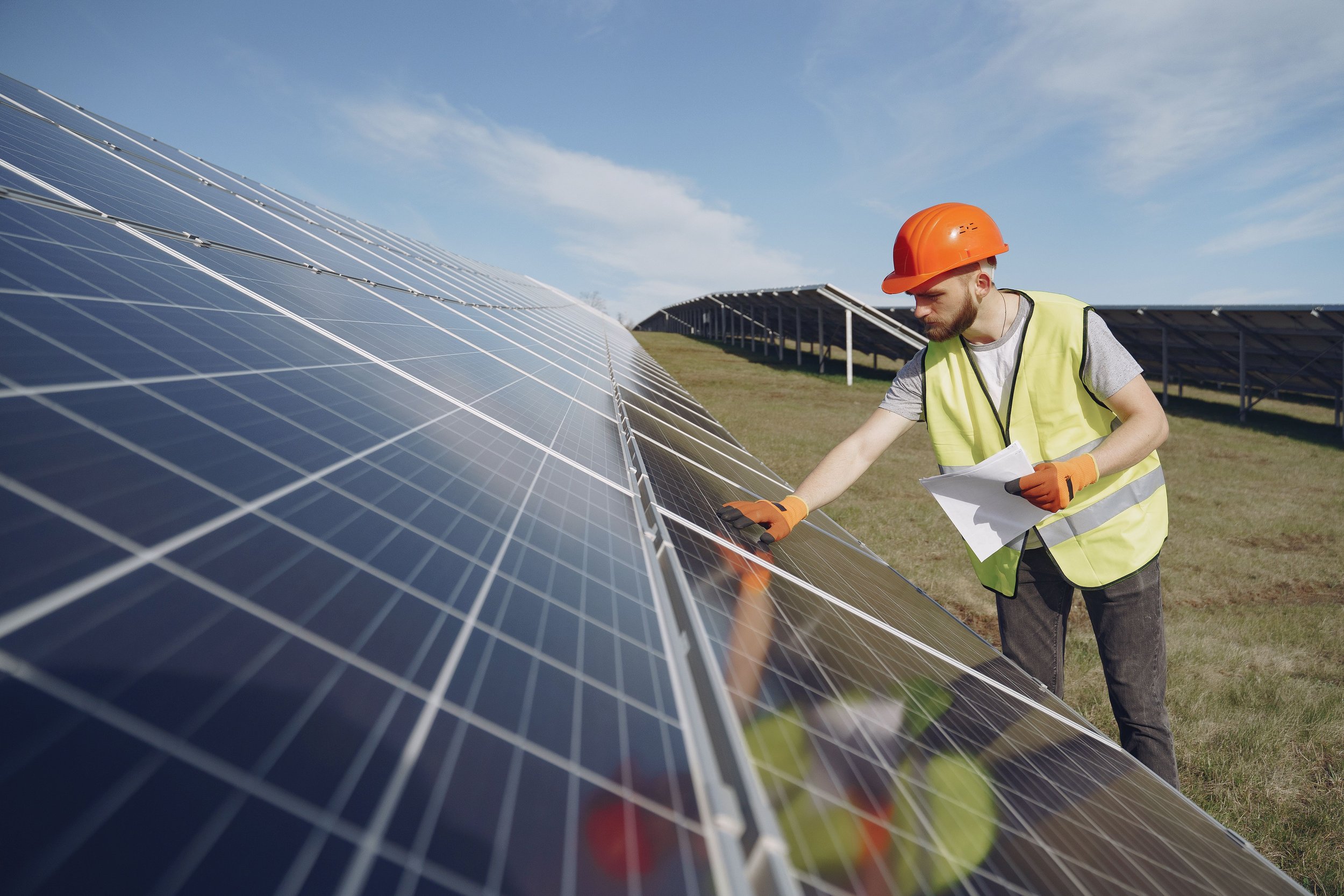 Solar installer inspecting photovoltaic panels on a large outdoor array.