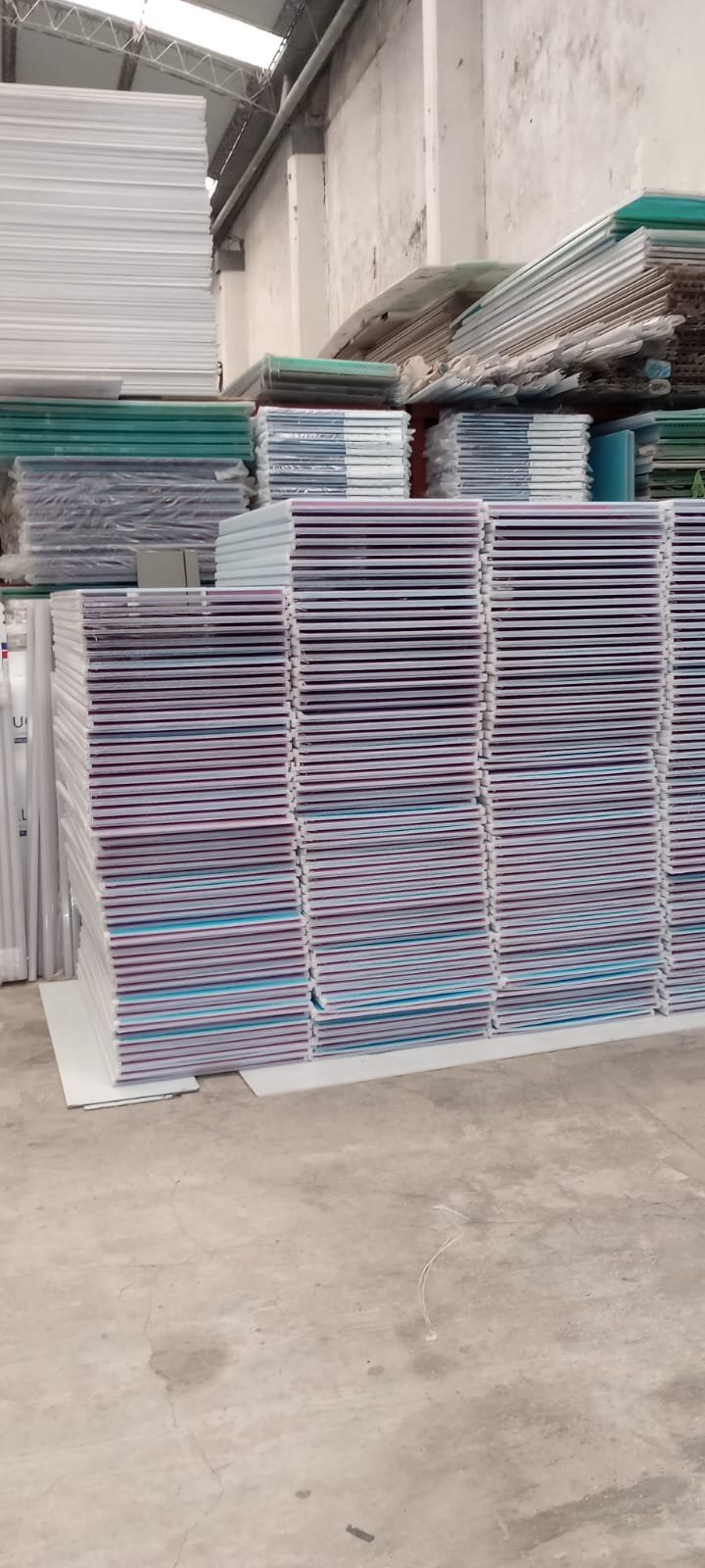 Stacks of various plastic materials, possibly surfboards or signs, in a warehouse or manufacturing setting.