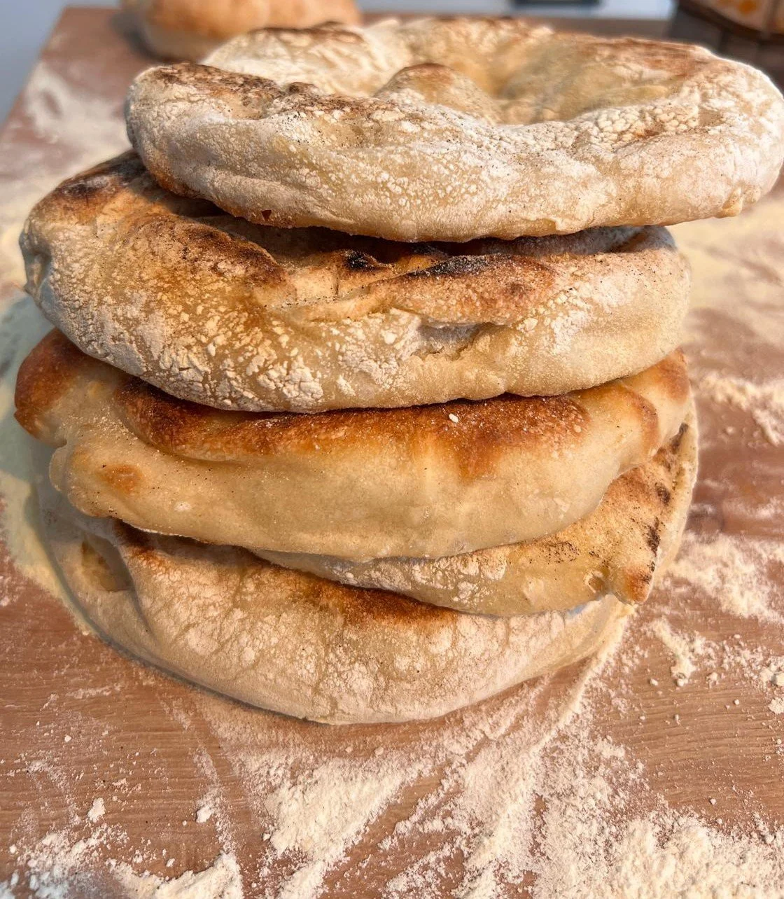 Four flatbreads stacked on a wooden surface with flour scattered around. Privatkoch Köln Ben Hiss Meal Prep