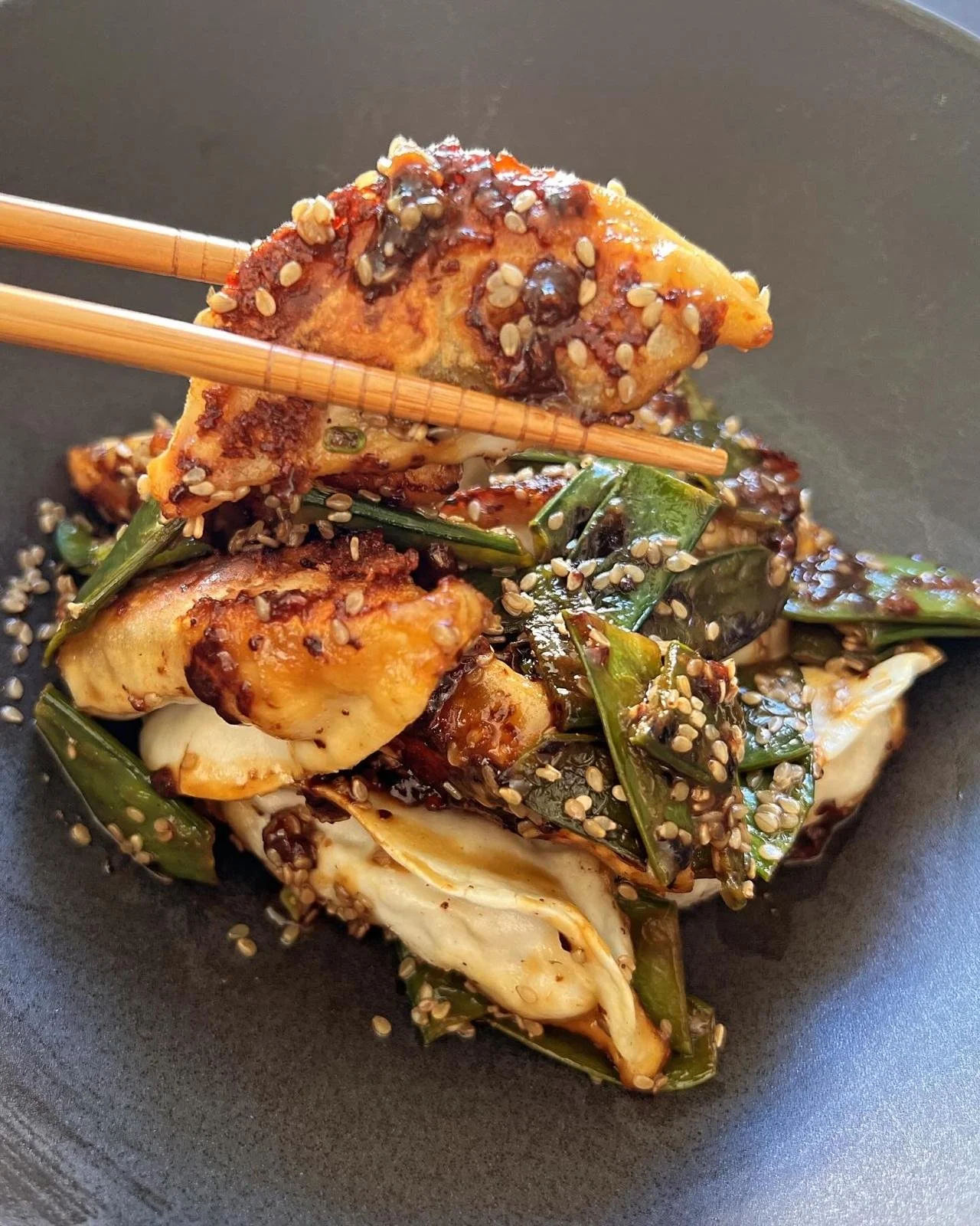 Chicken Gyozas with green beans, topped with sesame seeds in a black bowl Privatkoch Köln Ben Hiss Meal Prep Fußballer Soccer Football