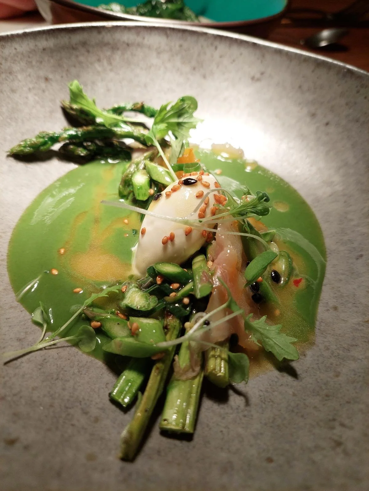 A bowl of green soup garnished with asparagus, microgreens, a soft boiled egg, and sprinkled with sesame seeds.Düsseldorf Köln Leverkusen Fußball Football Private Chef Private Meal Prep
