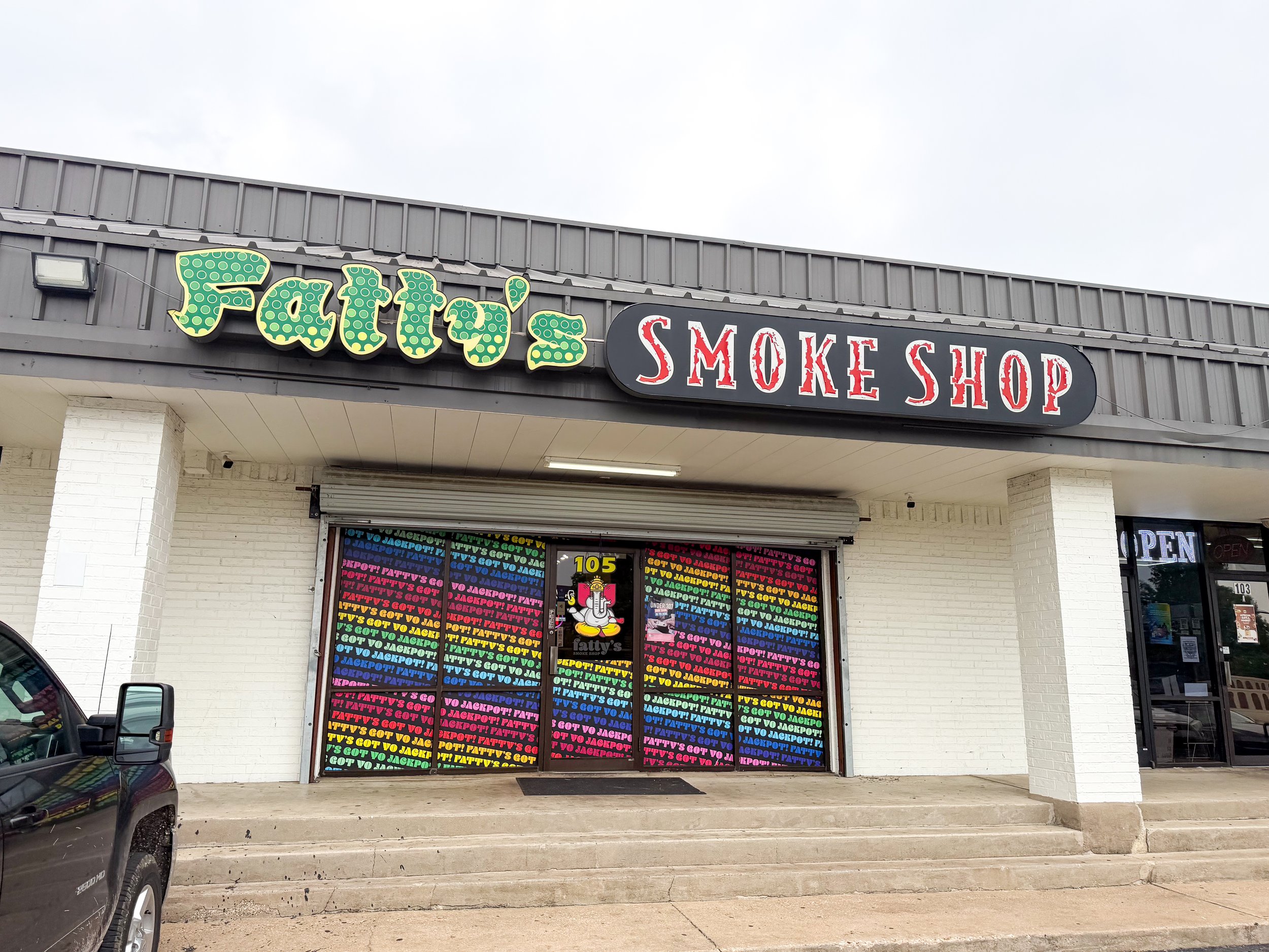 The storefront of Fatty's Smoke Shop in Navasota, Texas with a colorful sign and window display featuring a cartoon smoking character.
