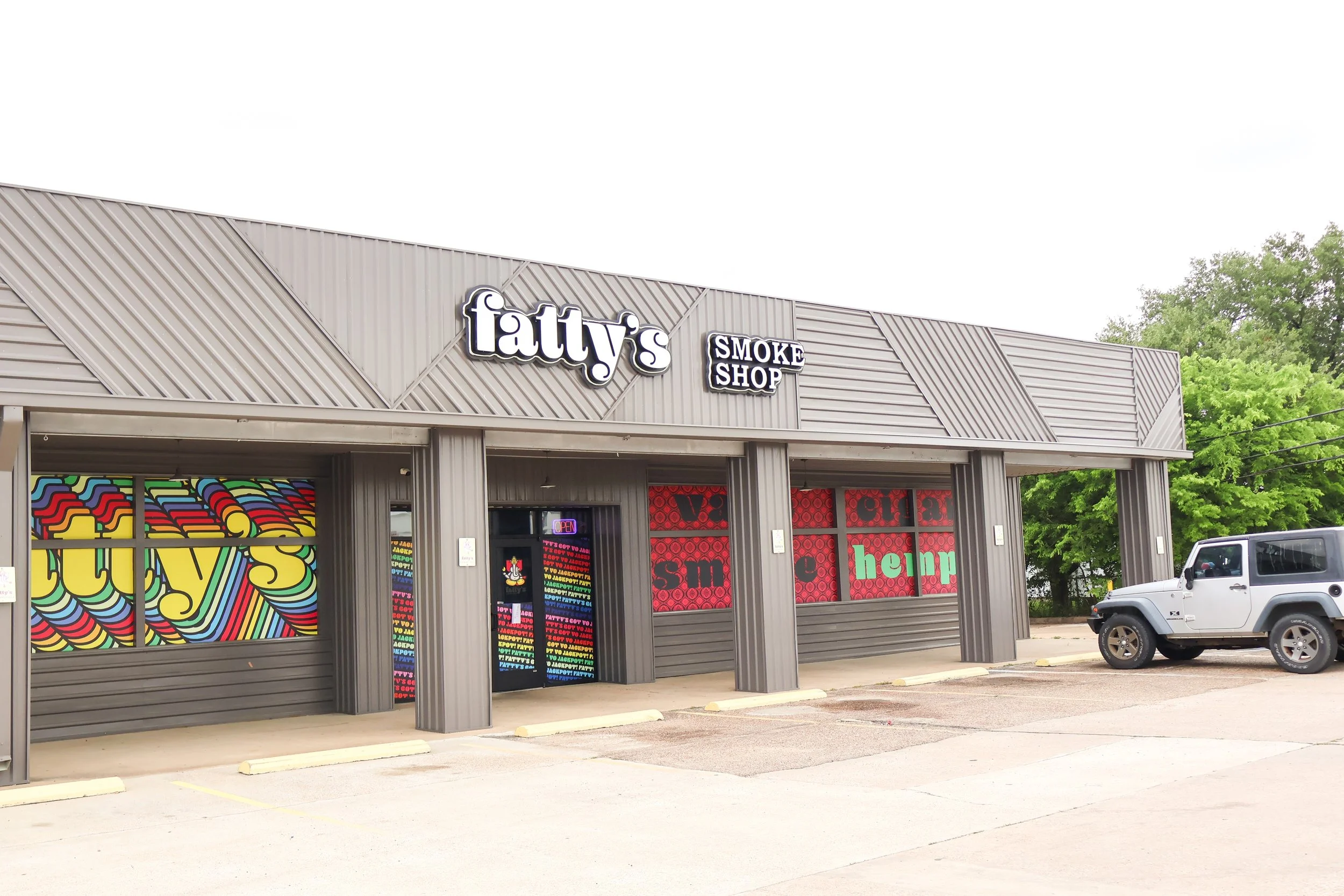 Front view of a Bryan, Texas commercial building with the sign 'Fatty's Smoke Shop' on the facade, colorful window displays