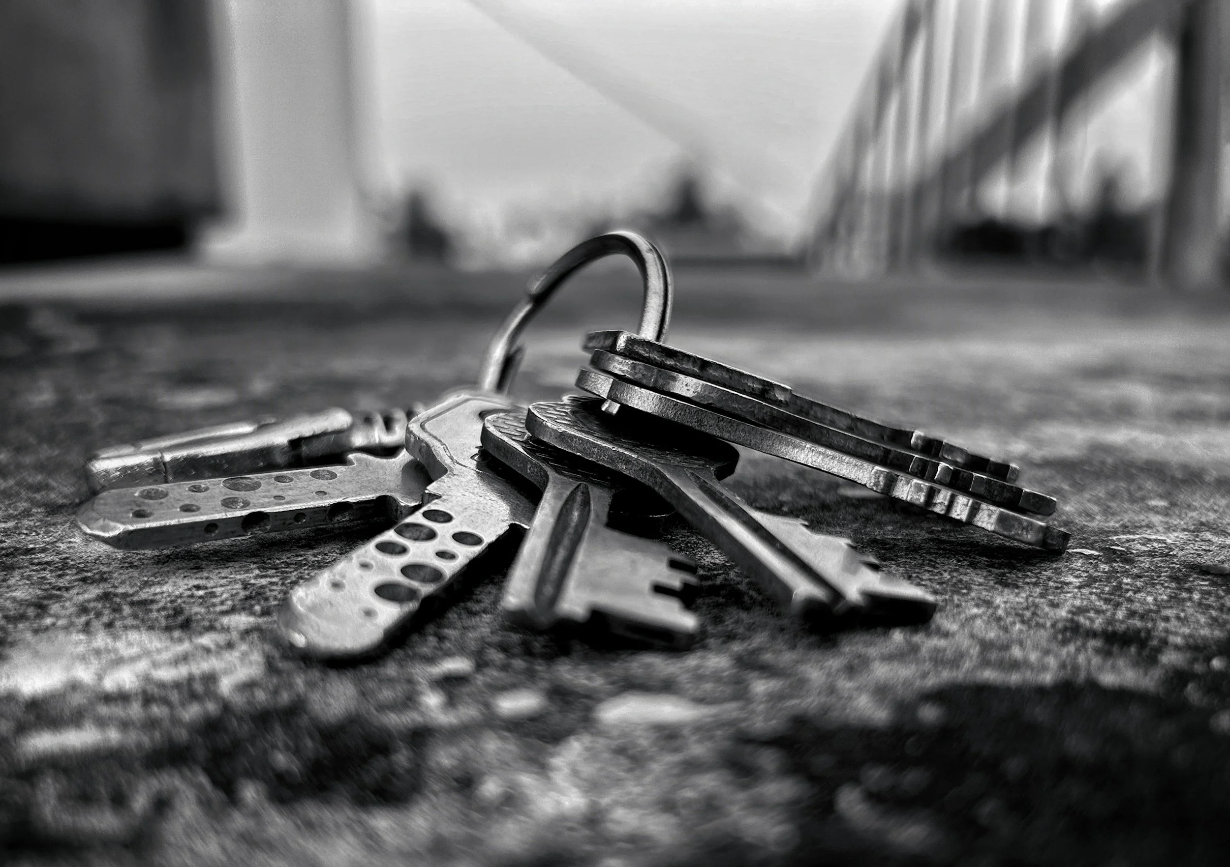 Close-up of a keychain with multiple keys lying on a textured surface, with a blurred background.