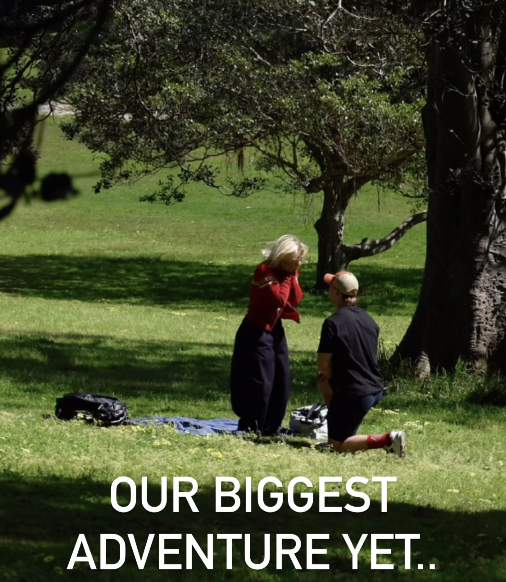 A woman and a young boy kneeling on grass in a park, engaging in a conversation, with trees and greenery in the background, and text that reads 'Our Biggest Adventure Yet..'